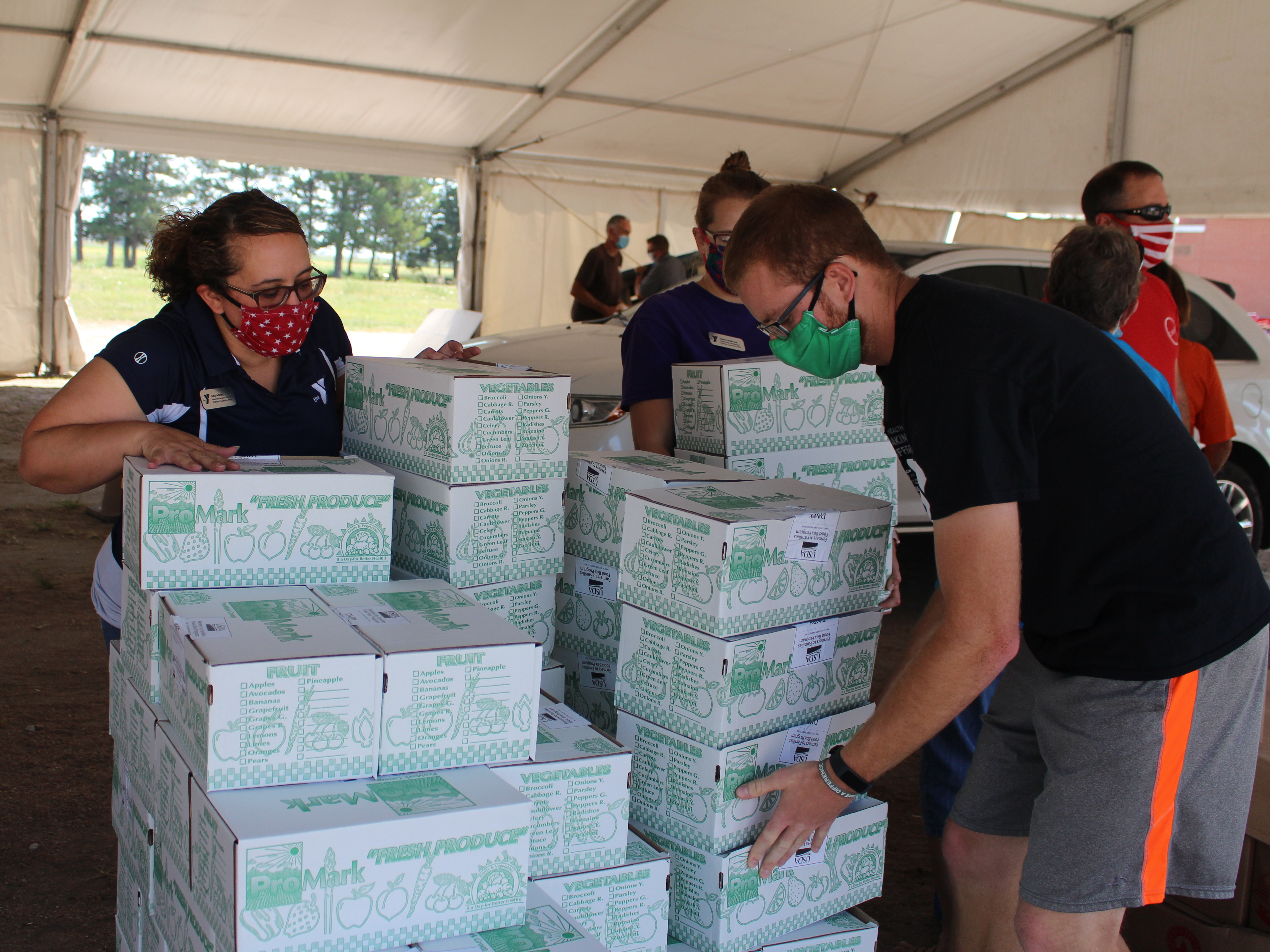 Each week, police in Lexington, Neb., cordon off several blocks near the edge of town, where roughly 700 cars will line up for USDA Farmers to Families food boxes. Above, volunteers organize boxes on Aug. 27, 2020. (Harvest Public Media)