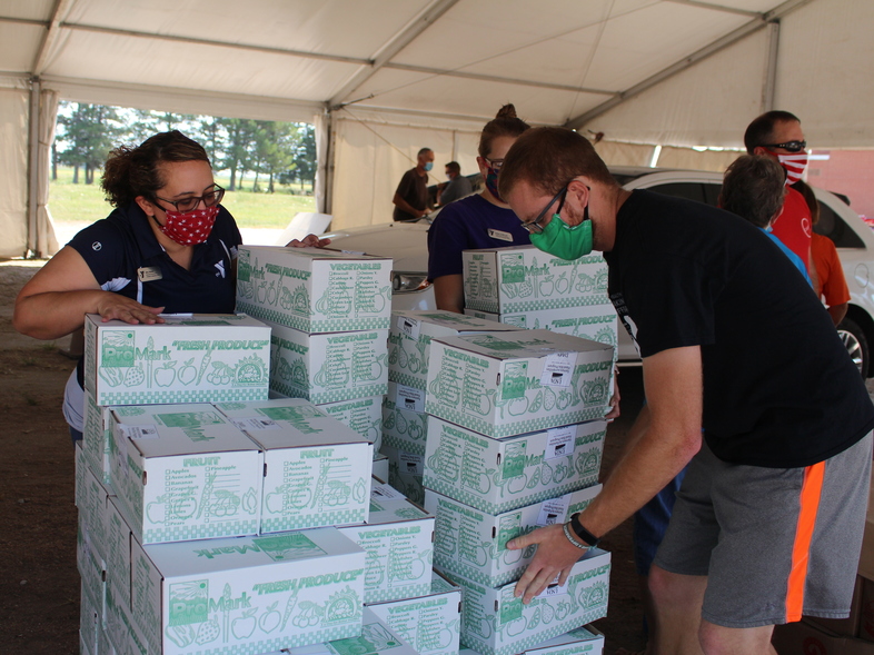 Each week, police in Lexington, Neb., cordon off several blocks near the edge of town, where roughly 700 cars will line up for USDA Farmers to Families food boxes. Above, volunteers organize boxes on Aug. 27, 2020. (Christina Stella/Harvest Public Media)