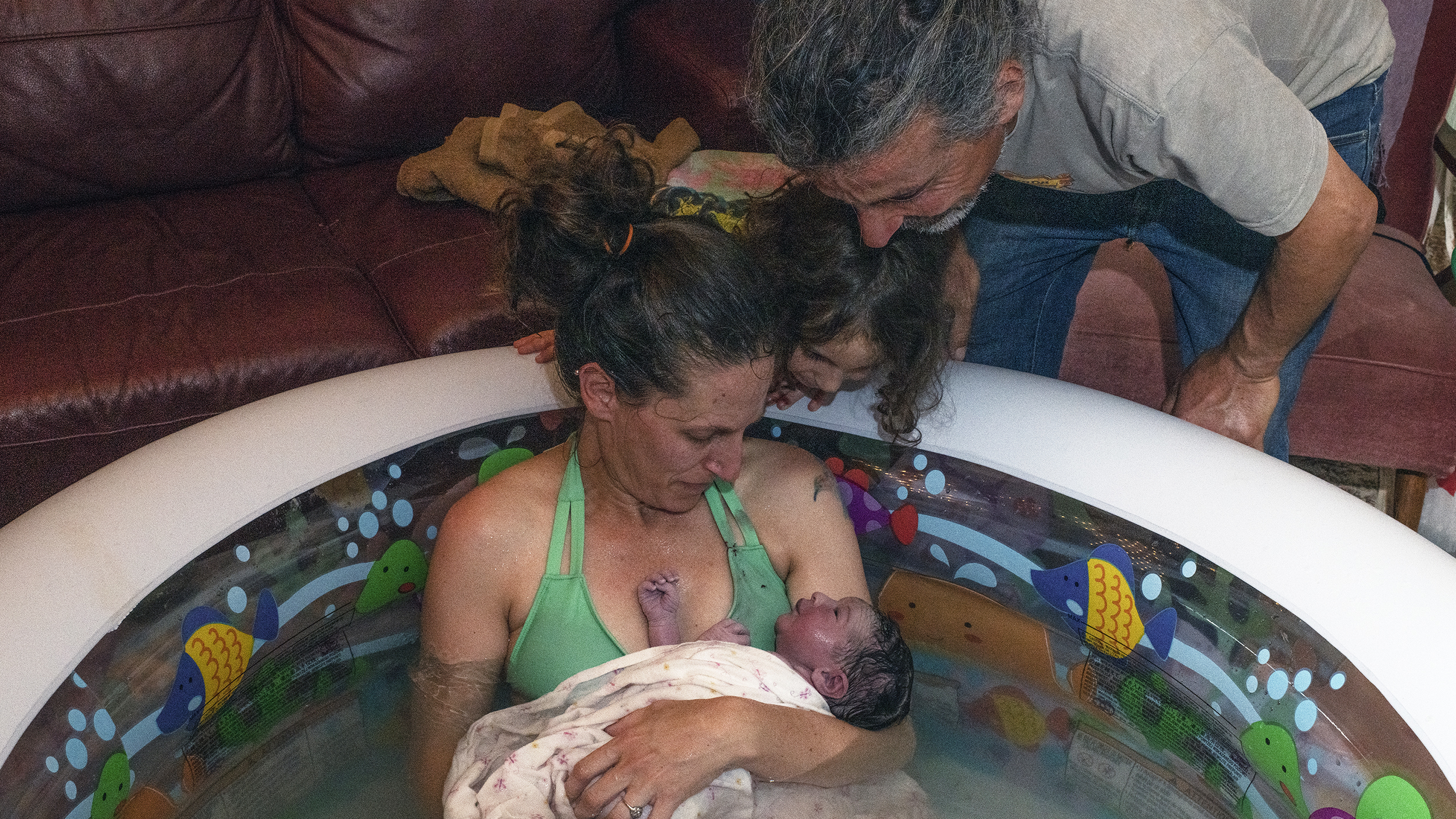 Morgan Cooper holds newborn Lourice as her husband Saleh Totah and 4-year-old son look on. Lourice was delivered in June in a home birth in an inflatable swimming pool in the family