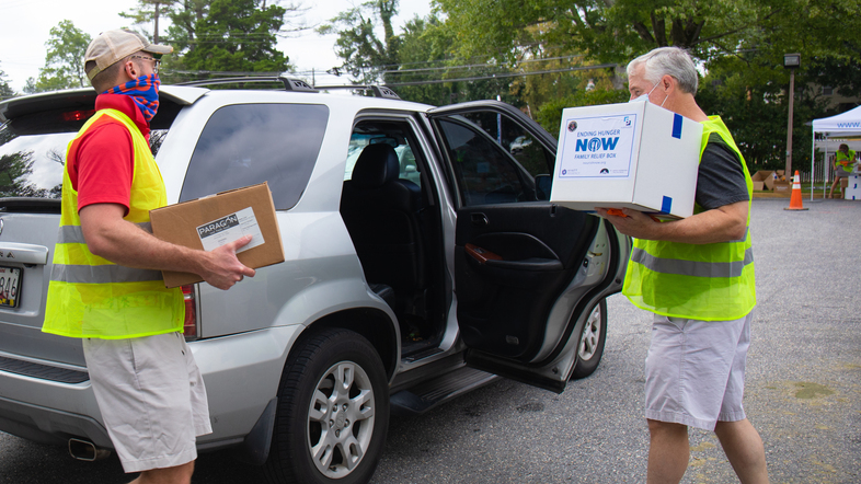 Volunteers from St. John's Episcopal Church in Bethesda help hand out food to a local resident at an event earlier this month. (Xueying Chang/NPR)