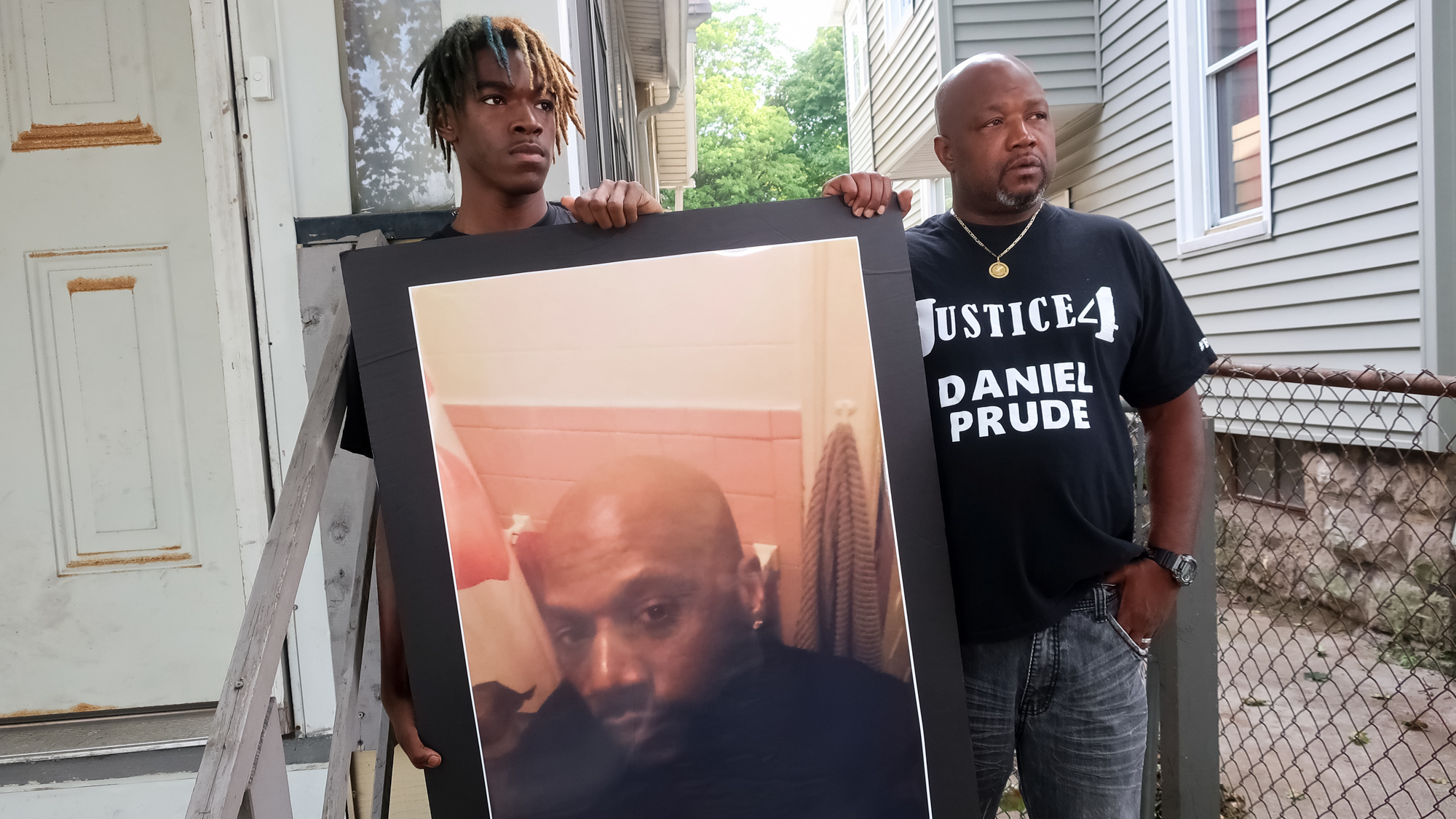 Family members Armin Prude (left) and Joe Prude stand with a picture of Daniel Prude in Rochester, N.Y., Thursday, Sept. 3, 2020. While suffering a mental health crisis, Prude, 41, suffocated after police in Rochester put a "spit hood" over his head while being taken into custody. He died March 30 after he was taken off life support, seven days after the encounter with police.