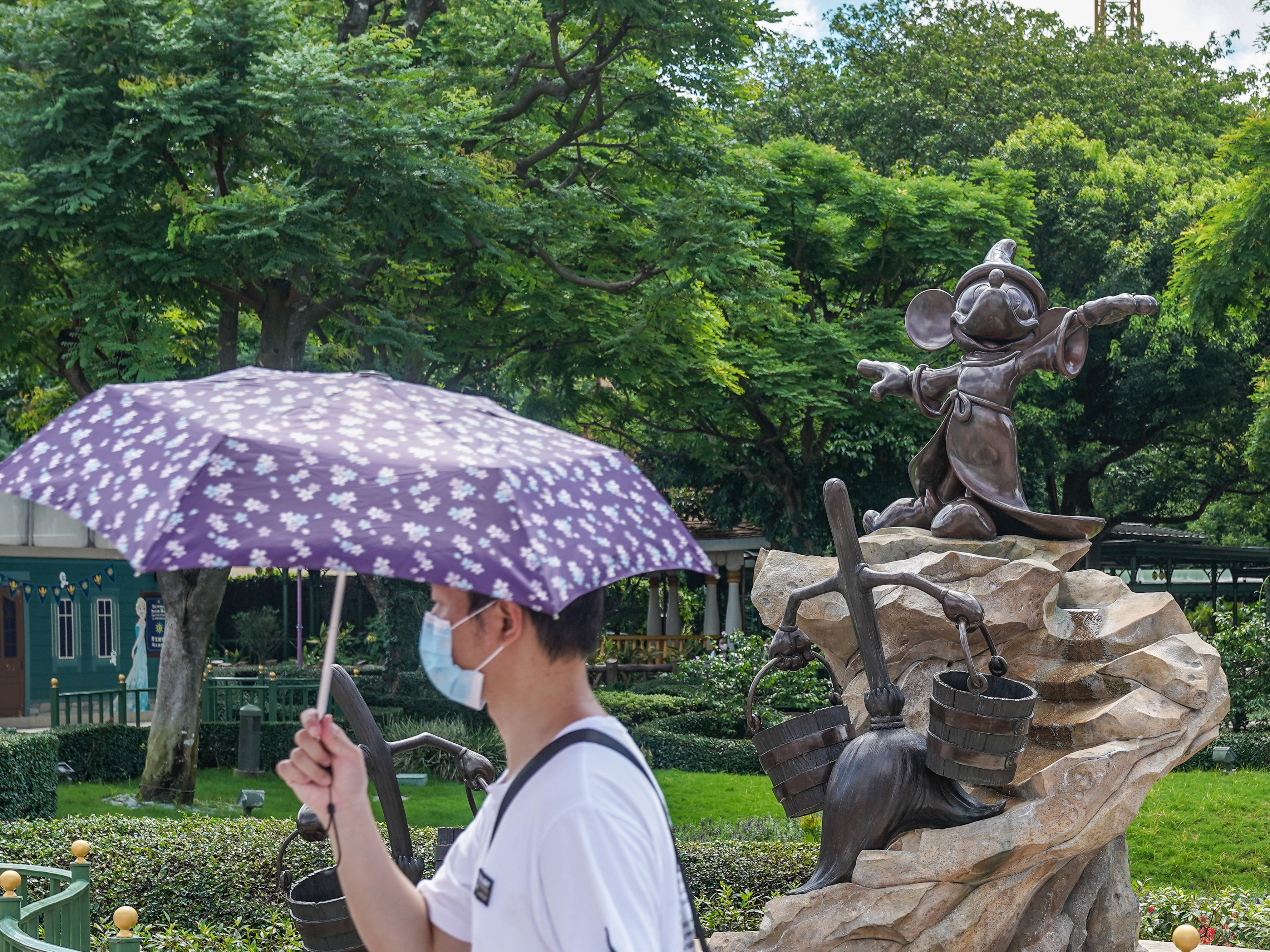 A visitor wears a mask while walking by Mickey Mouse at Hong Kong Disneyland. (Bloomberg via Getty Images)