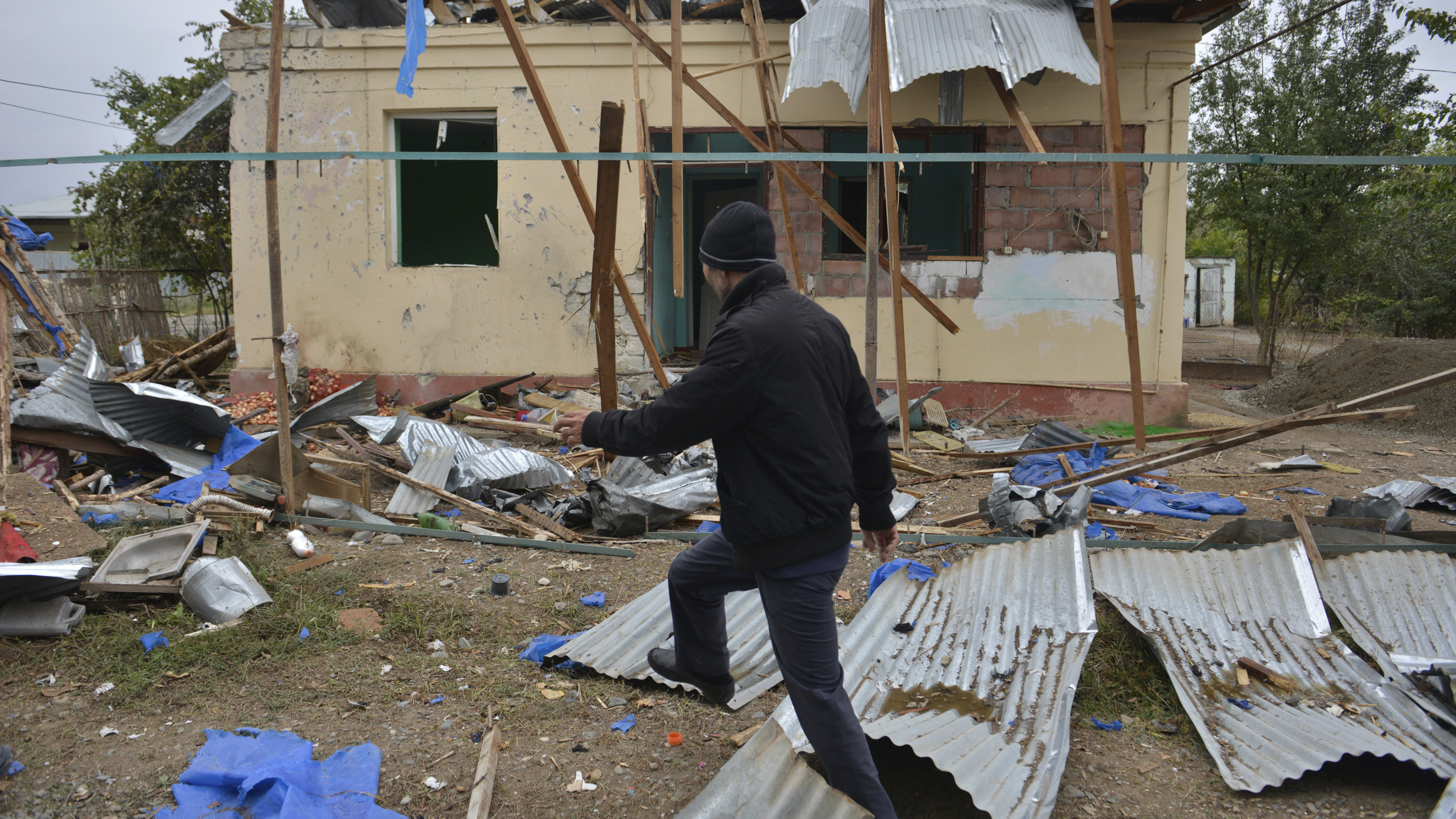 A man walks past a house destroyed by shelling during fighting over Nagorno-Karabakh in Agdam, Azerbaijan, on Oct. 1. The International Committee of the Red Cross says civilian deaths and injuries have been reported.