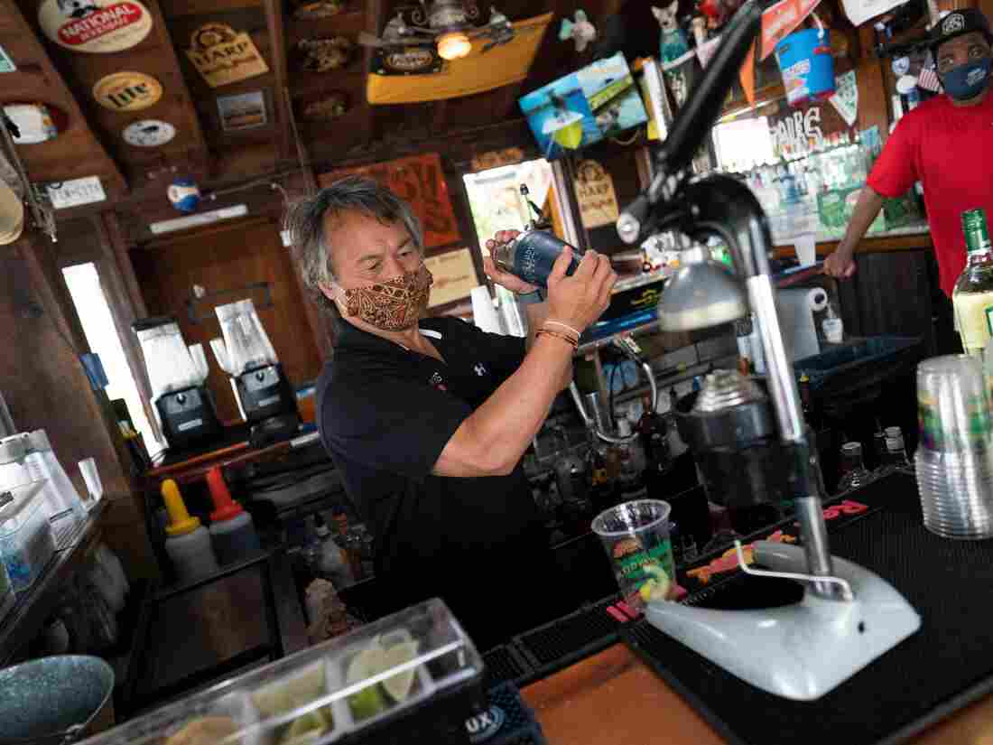 A bartender wearing a facemask makes drinks as Fish Tails bar and grill opens for in person dining, amid the coronavirus pandemic- (Photo by Alex Edelman / AFP) (Photo by ALEX EDELMAN/AFP via Getty Images)
