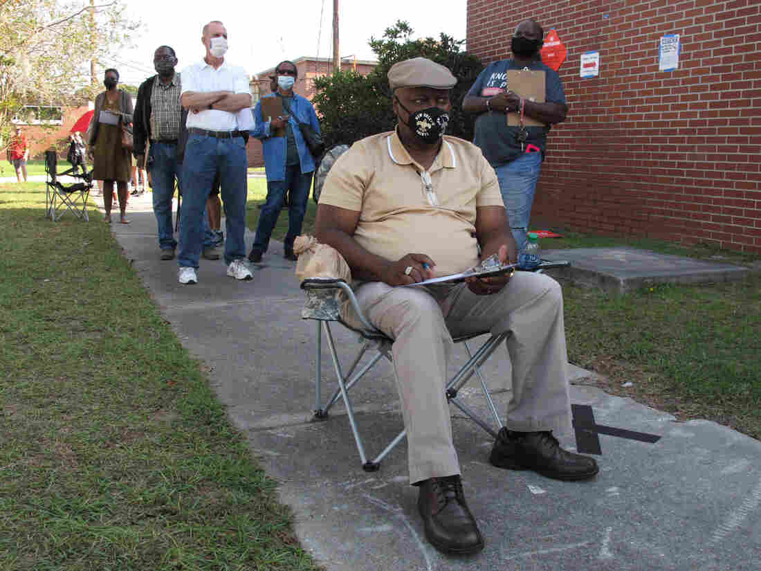 Richard Williams sits in a folding chair, filling out paperwork, as he waits in line to vote early in Savannah, Ga., on Wednesday. Black people are going to the polls by the thousands and waiting in lines for hours to vote early in Georgia.