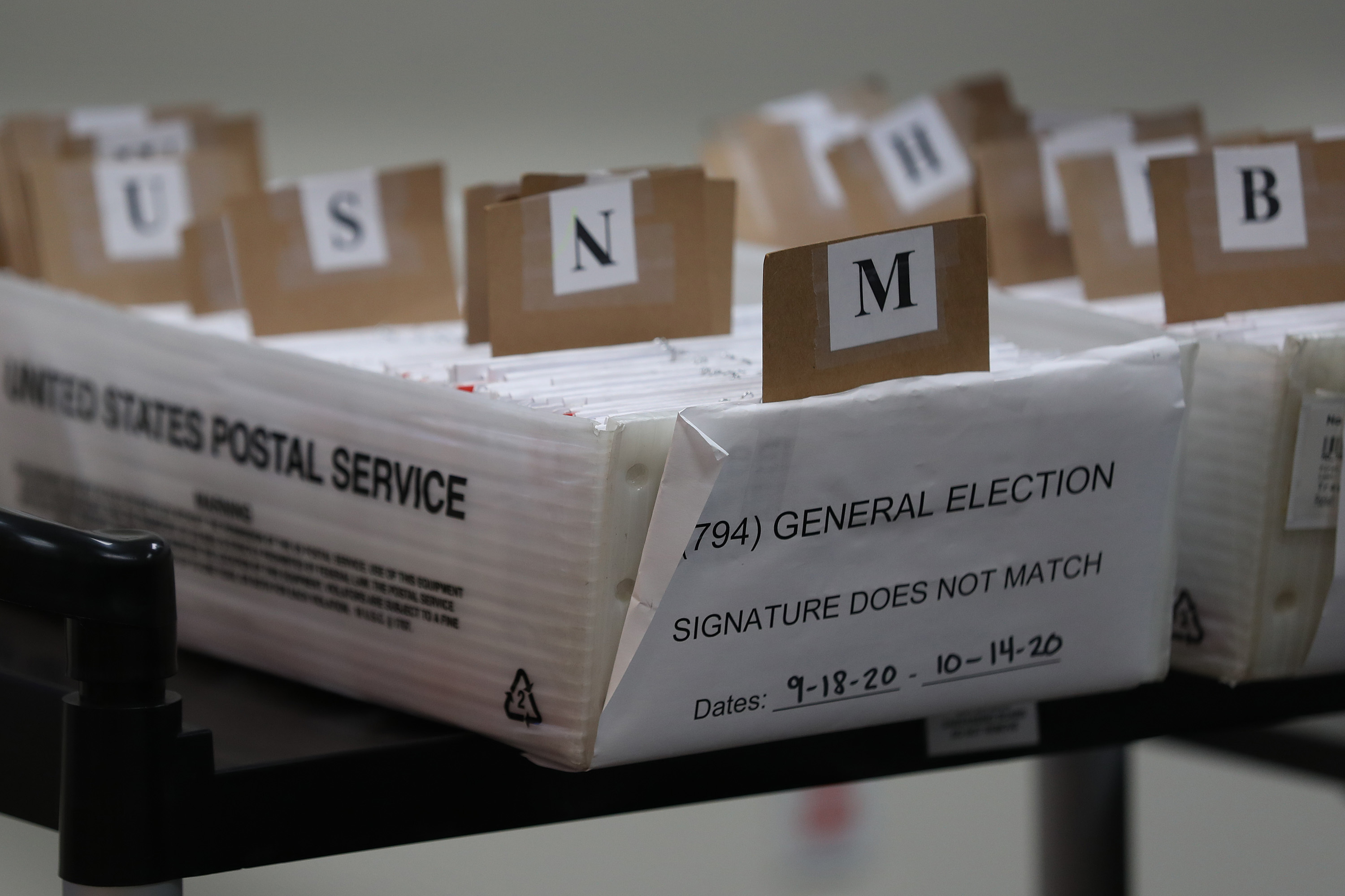 Mail-in ballots that need to be reviewed because of signature discrepancies sit in boxes at the Miami-Dade County Elections Department in Doral, Fla., on Oct. 15. Signature problems are a frequent reason that ballots are rejected, though many states allow voters to fix those problems before Election Day. (Getty Images)