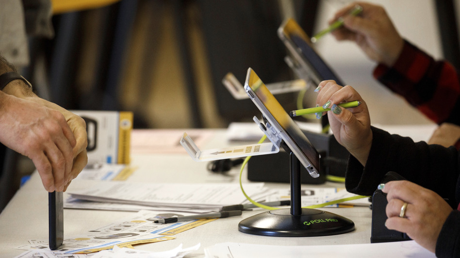 An election worker uses an electronic pollbook to check voters at a polling station in the Echo Park Recreation Complex in Los Angeles on March 3, 2020.