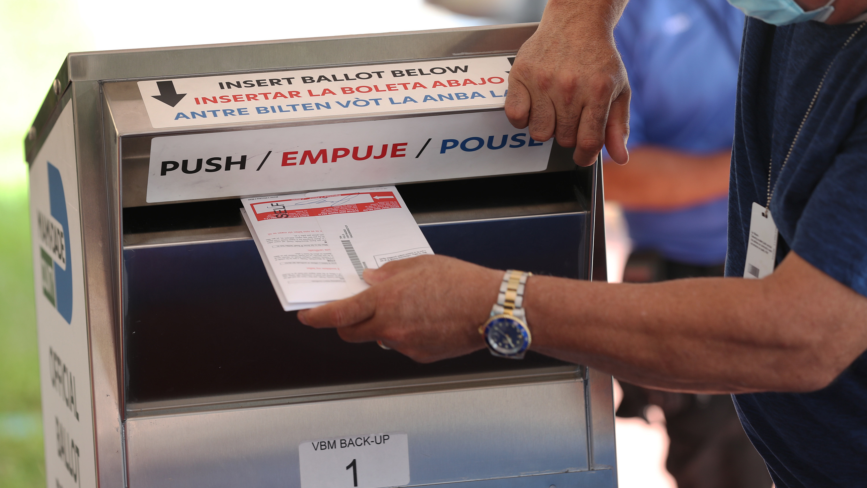 A poll worker places vote-by mail ballots into a ballot box this month at the Miami-Dade County Election Department headquarters in Doral, Fla. Voters in Florida are among those who have reported receiving emails threatening them to vote for President Trump. (Getty Images)