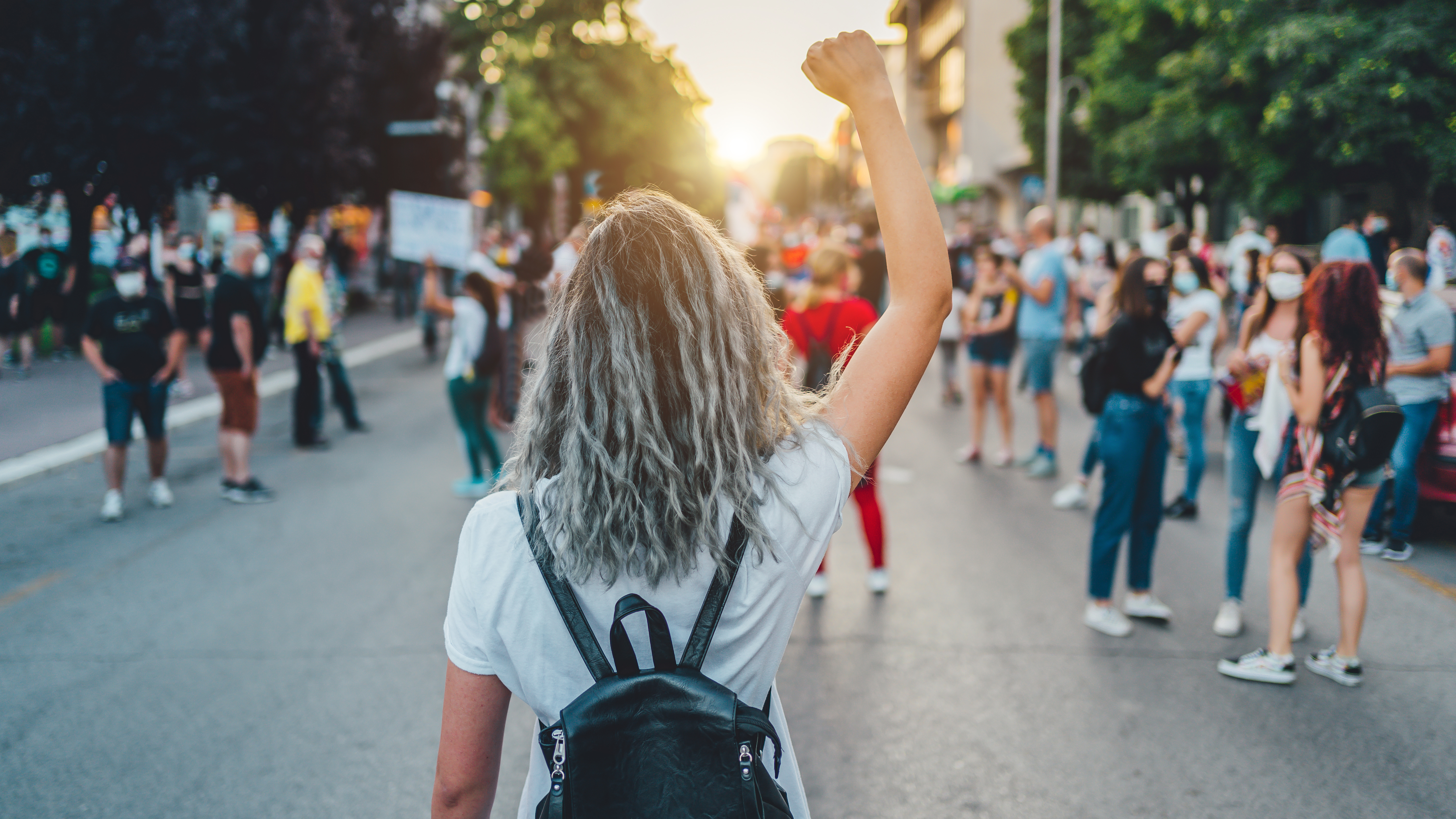 Young woman with a raised fist protests in the street.