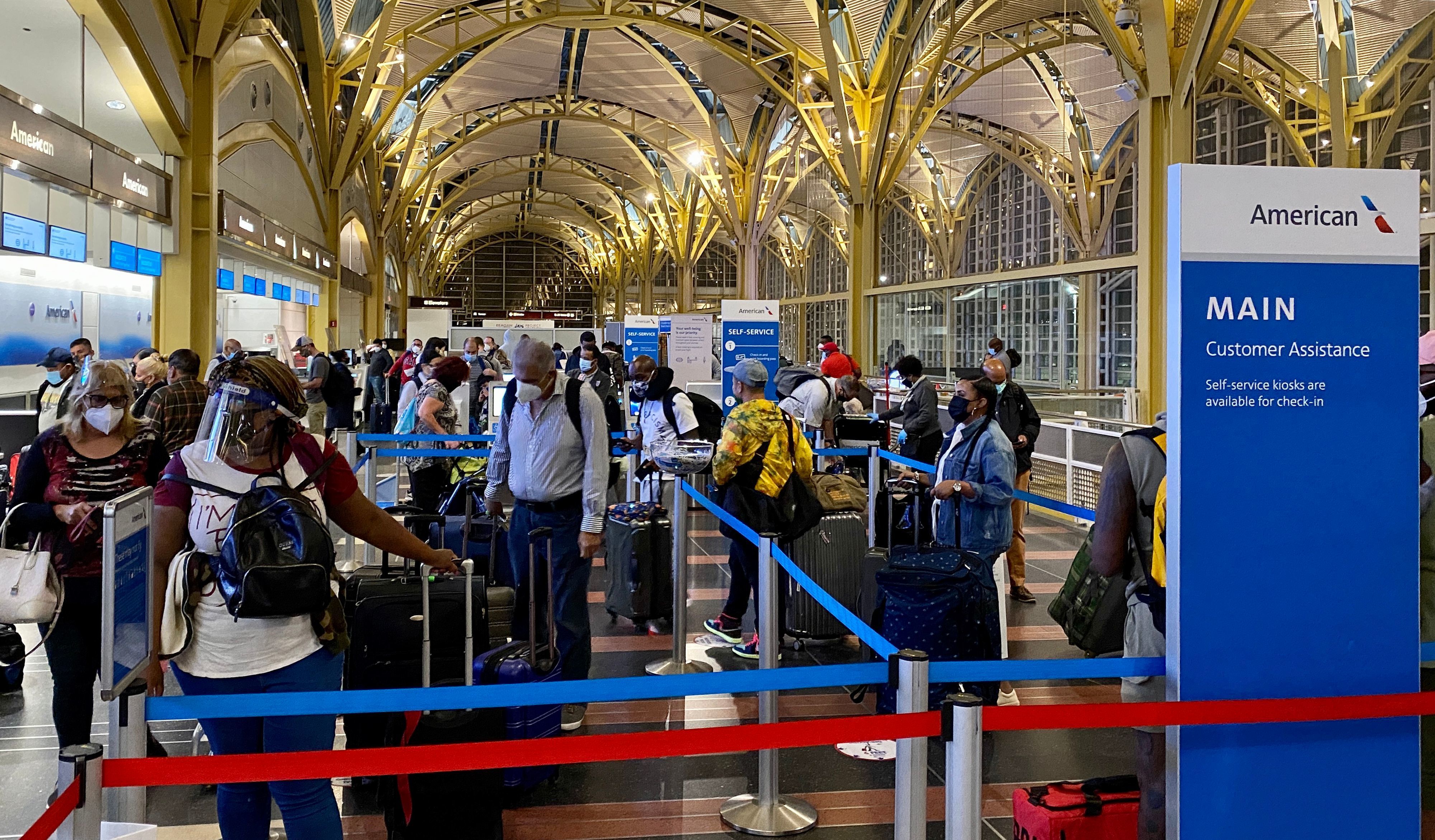 Passengers queue at the American Airlines counter at Ronald Reagan National Airport on Sept. 17. Coronavirus cases are surging across the country as the holiday season approaches, leaving many families with questions about traveling to gather together. (AFP via Getty Images)
