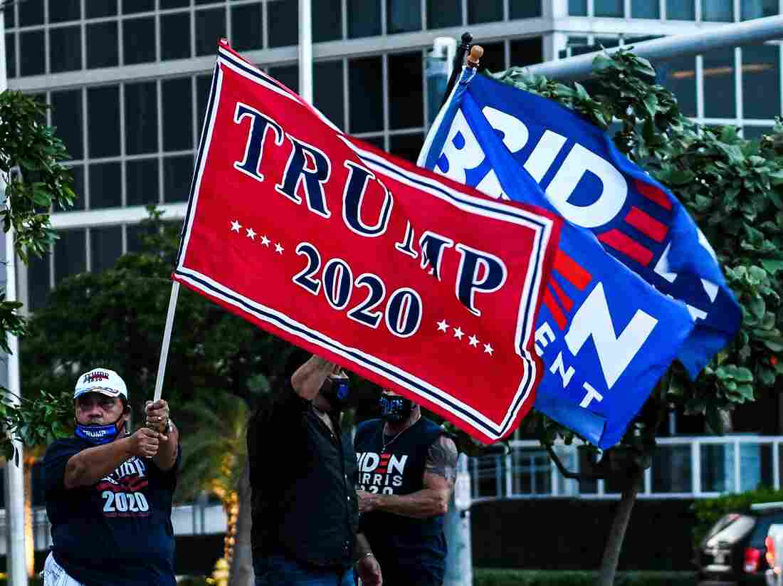 Supporters of US President Donald Trump and Democratic presidential nominee and former Vice President Joe Biden wave flags prior to Biden's arrival for an NBC townhall outside of the Perez Art Museum in Miami, Florida on October 5, 2020. (Photo by CHANDAN KHANNA / AFP) (Photo by CHANDAN KHANNA/AFP via Getty Images)
