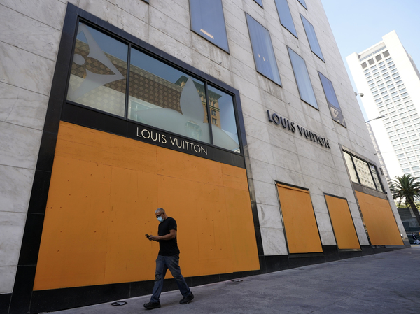 A man walks past a boarded-up window of a Louis Vuitton store in San Francisco on Sunday.