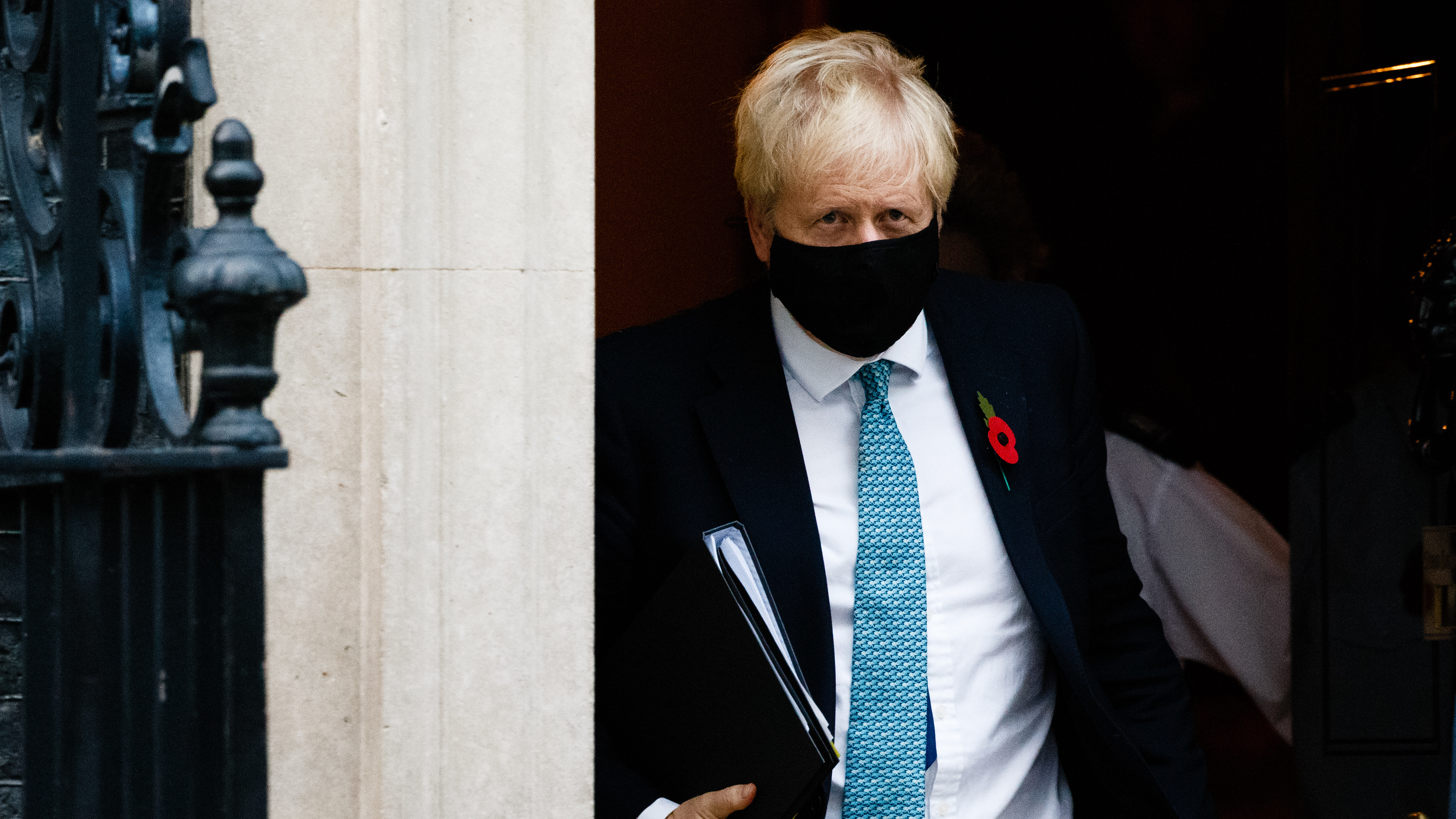 British Prime Minister Boris Johnson wears a mask and remembrance poppy as he leaves No. 10 Downing St. heading for the Houses of Parliament in London after ordering a new England-wide coronavirus lockdown.