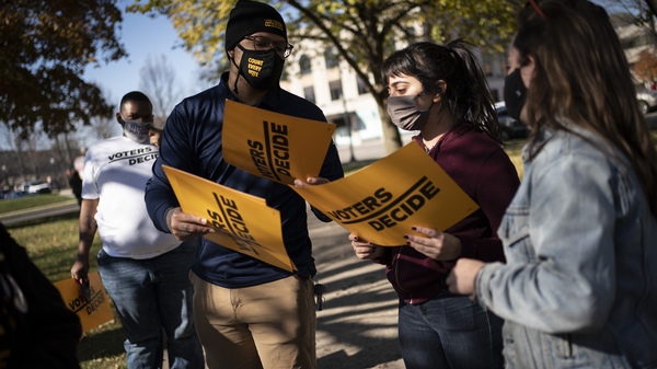 People gather with signs that read "Voters Decide" at the Civic Center Park while waiting for the results of election in Kenosha, Wis. on Wednesday.