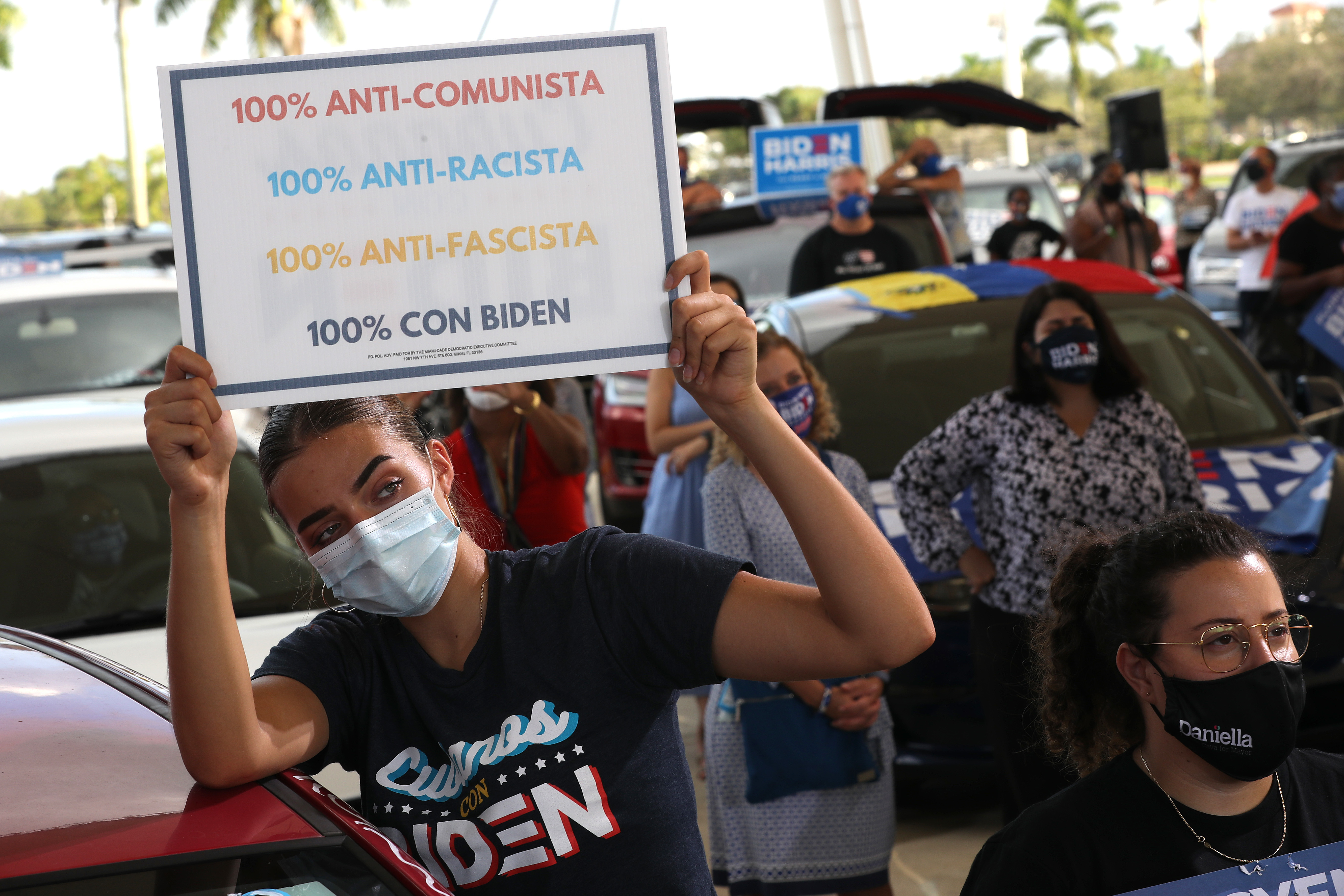 Wearing a face masks to reduce the risk posed by the coronavirus, Sophia Hildalgo (L) and Amore Rodriguez of Miami stay with their car decorated in Cubans for Biden paint. (Chip Somodevilla / Getty Images)