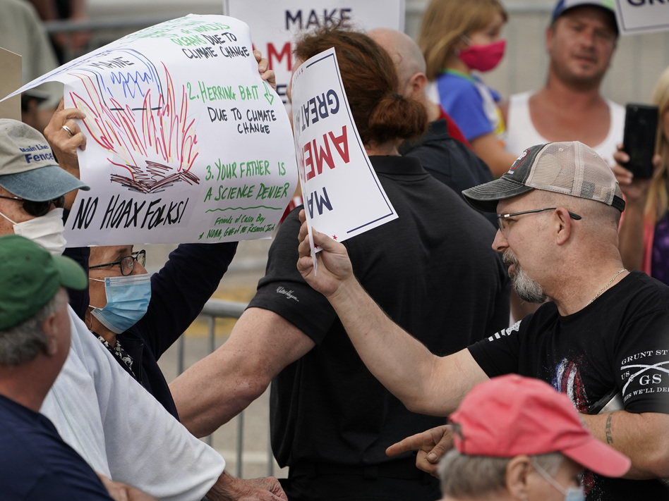 At a Saco, Maine, campaign rally for President Trump in September, a protester holding a sign detailing the effects of climate change on the Gulf of Maine (left) came face to face with Trump supporters who had different views. (Robert F. Bukaty/AP)