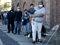 A woman holds her 1-year-old son as they wait in line to get a coronavirus test.