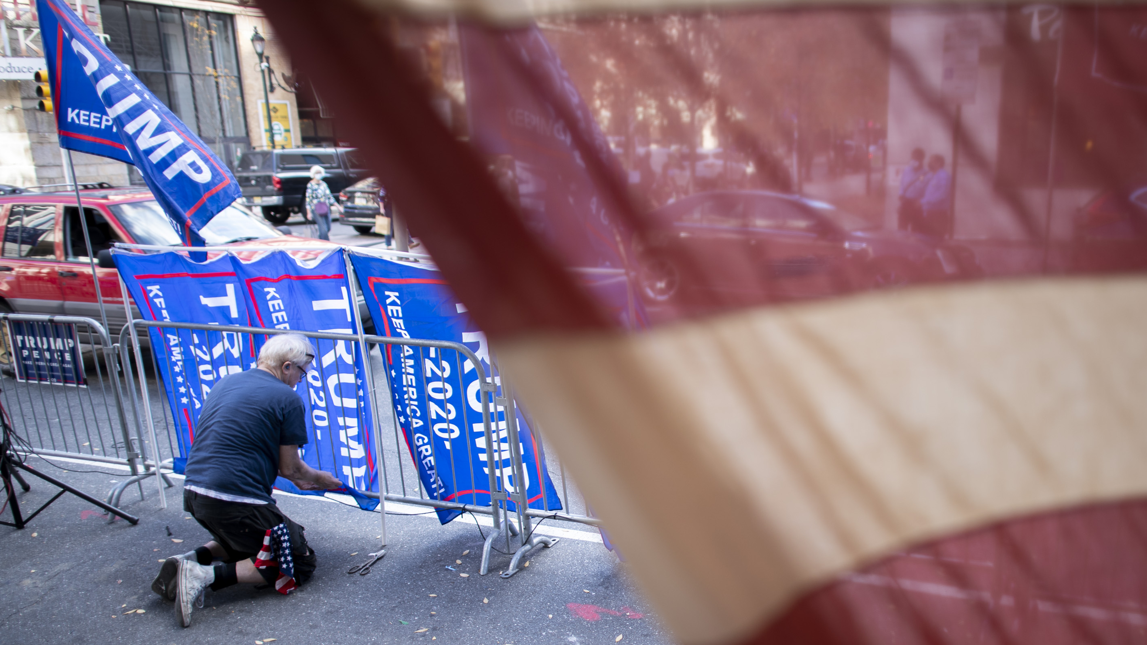 A supporter of President Trump fastens Trump campaign flags to a police barricade last week in Philadelphia. (Getty Images)