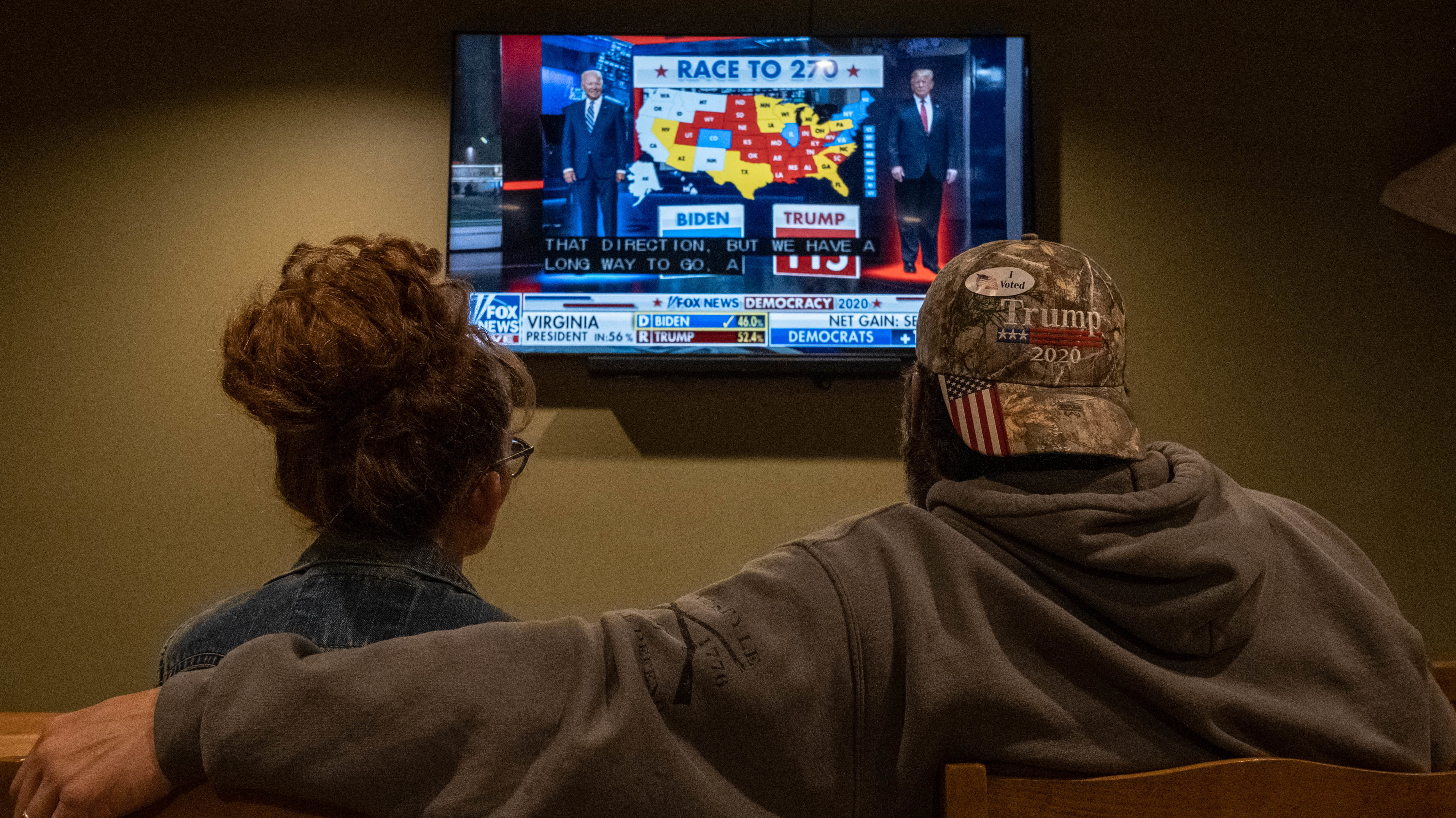 A couple watches the election results at a Republican watch party at Huron Valley Guns in New Hudson, Mich. People watching the results come in saw President Trump outperforming his position in preelection polls. (AFP via Getty Images)
