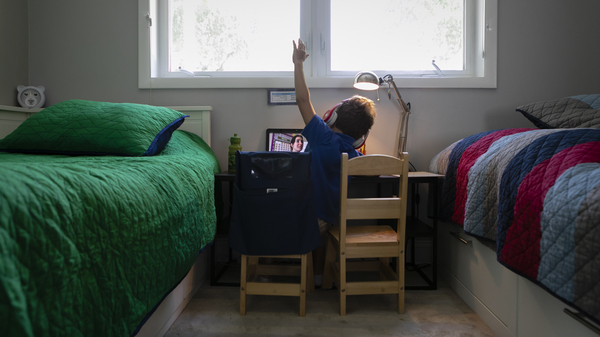 A student raises his hand while attending an online class from home in Miami on Sept. 3.