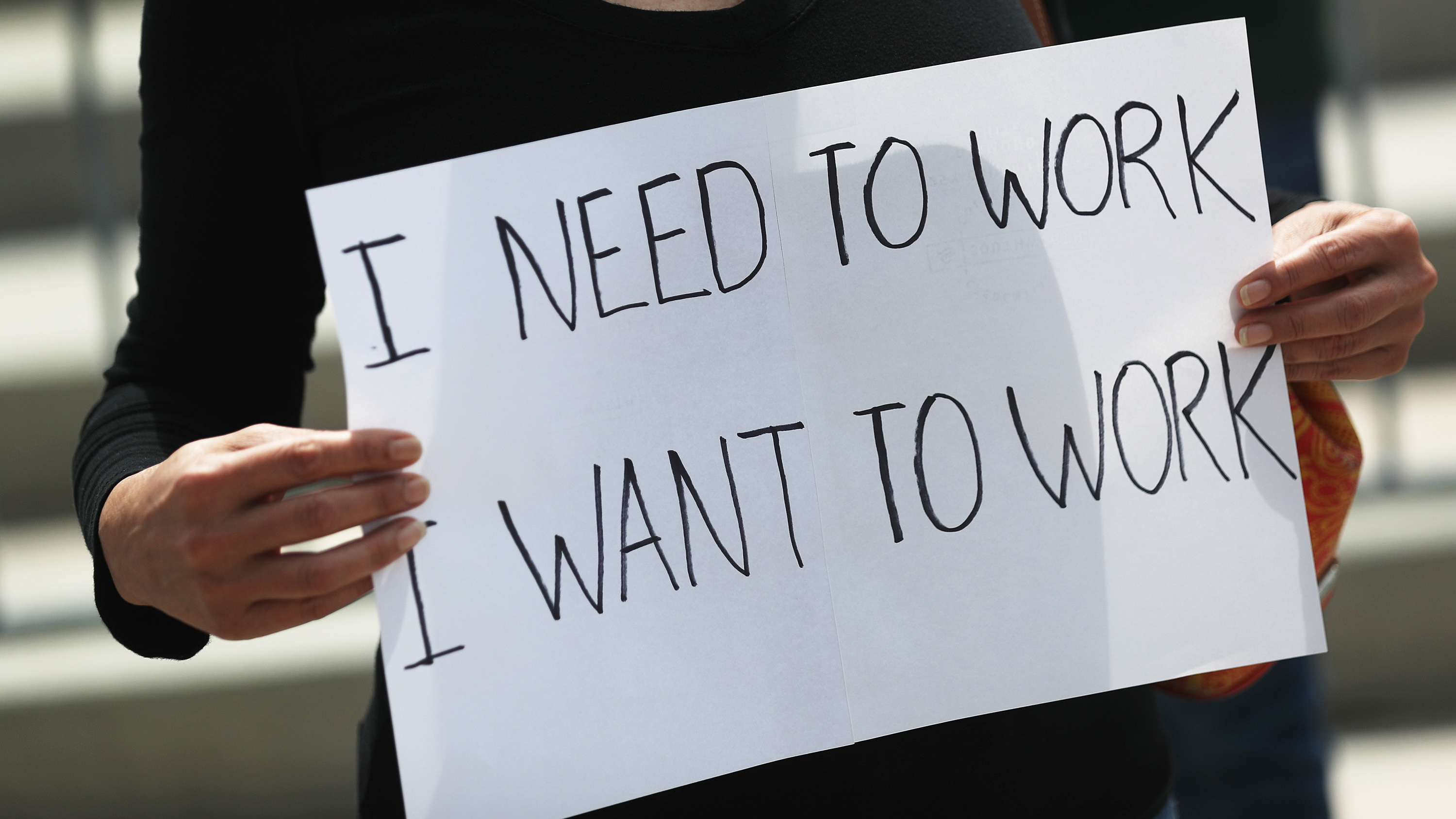 A protester holds a sign as she joins with restaurant owners, workers and supporters on July 10, 2020, to protest measures in Miami to close indoor seating amid a rise in coronavirus cases. The number of unemployment claims rose for a second week, reinforcing concerns about the economy.