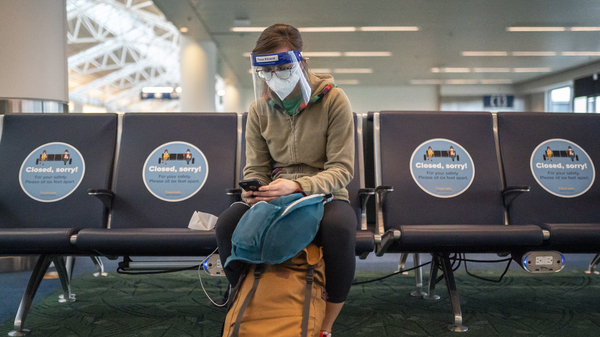 A traveler waits for a flight at Portland International Airport last week in Oregon. Public health experts say it