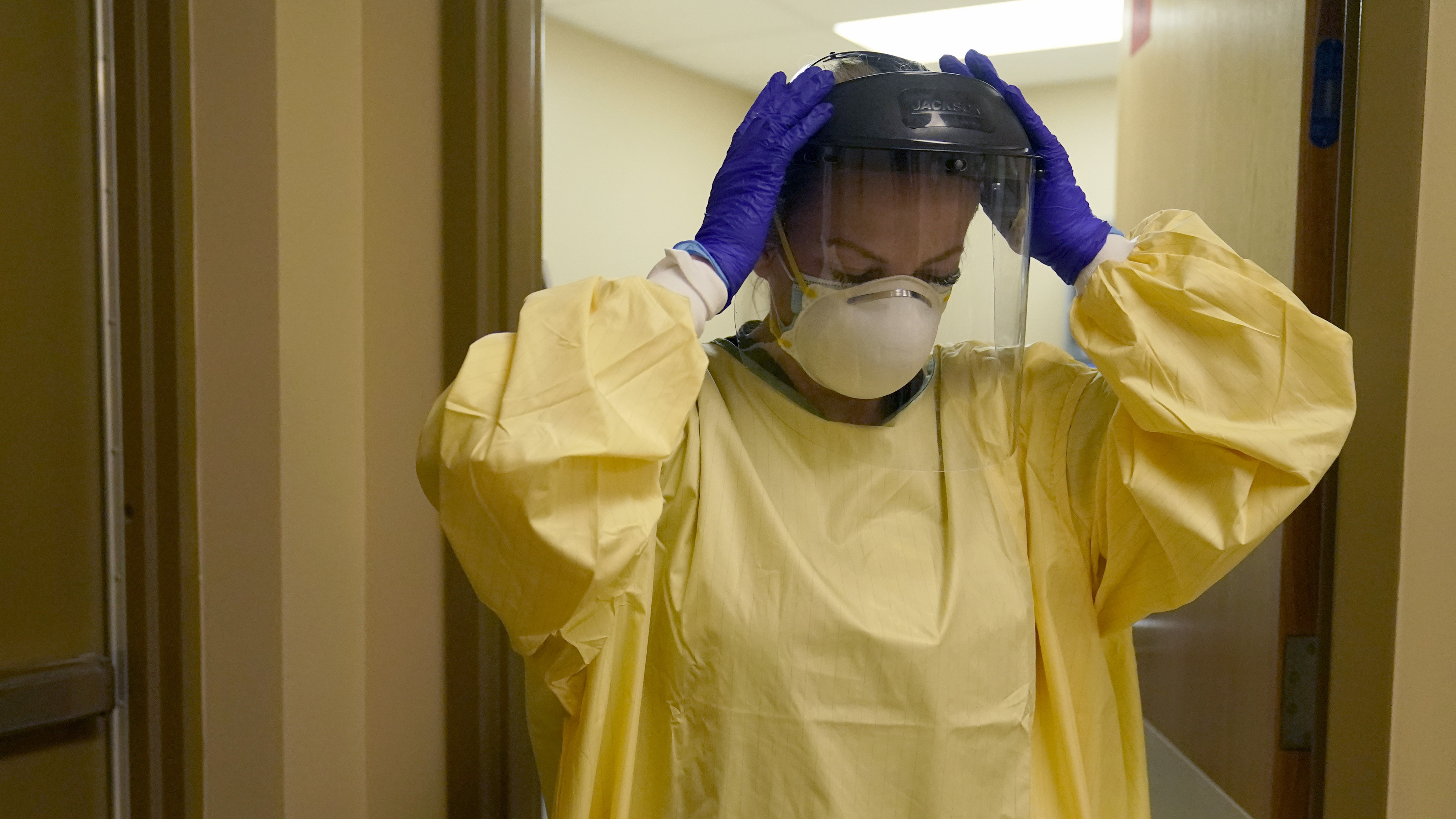 A nurse puts on personal protective equipment as she prepares to treat a COVID-19 patient last month at a rural Missouri hospital.