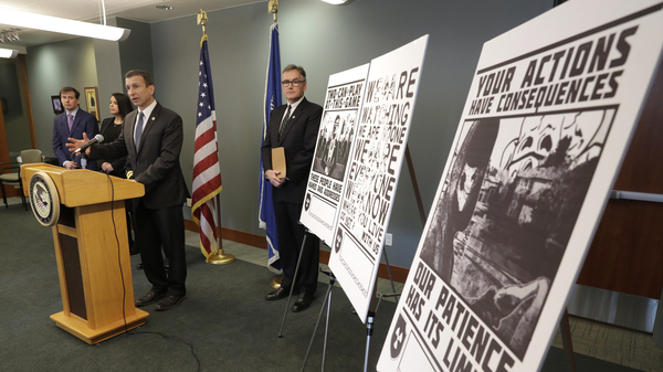 Raymond Duda, FBI Special Agent in Charge in Seattle, speaks in February about charges against a group of alleged members of the neo-Nazi group Atomwaffen Division for cyber-stalking and mailing threatening communications, including the posters at right, in a campaign against journalists in several cities.