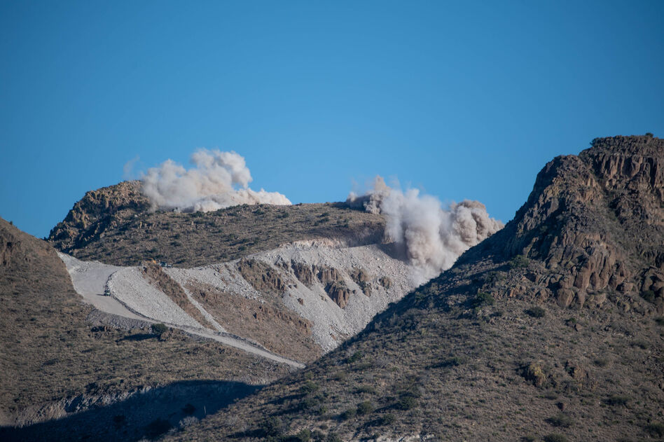 Dynamite raises clouds of dust above Guadalupe Canyon, near the New Mexico-Arizona border. The Diamond A Ranch, which is located next to the construction site, has sued the government, claiming the blasting has sent "car-sized boulders tumbling down onto ranch property." (John Kurc)