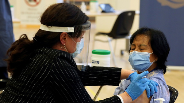 A health care worker administers a Pfizer-BioNTech COVID-19 vaccine to personal support worker Anita Quidangen at The Michener Institute, in Toronto, Canada, on Monday. Quidangen was one of the first people in Canada to receive the shot.