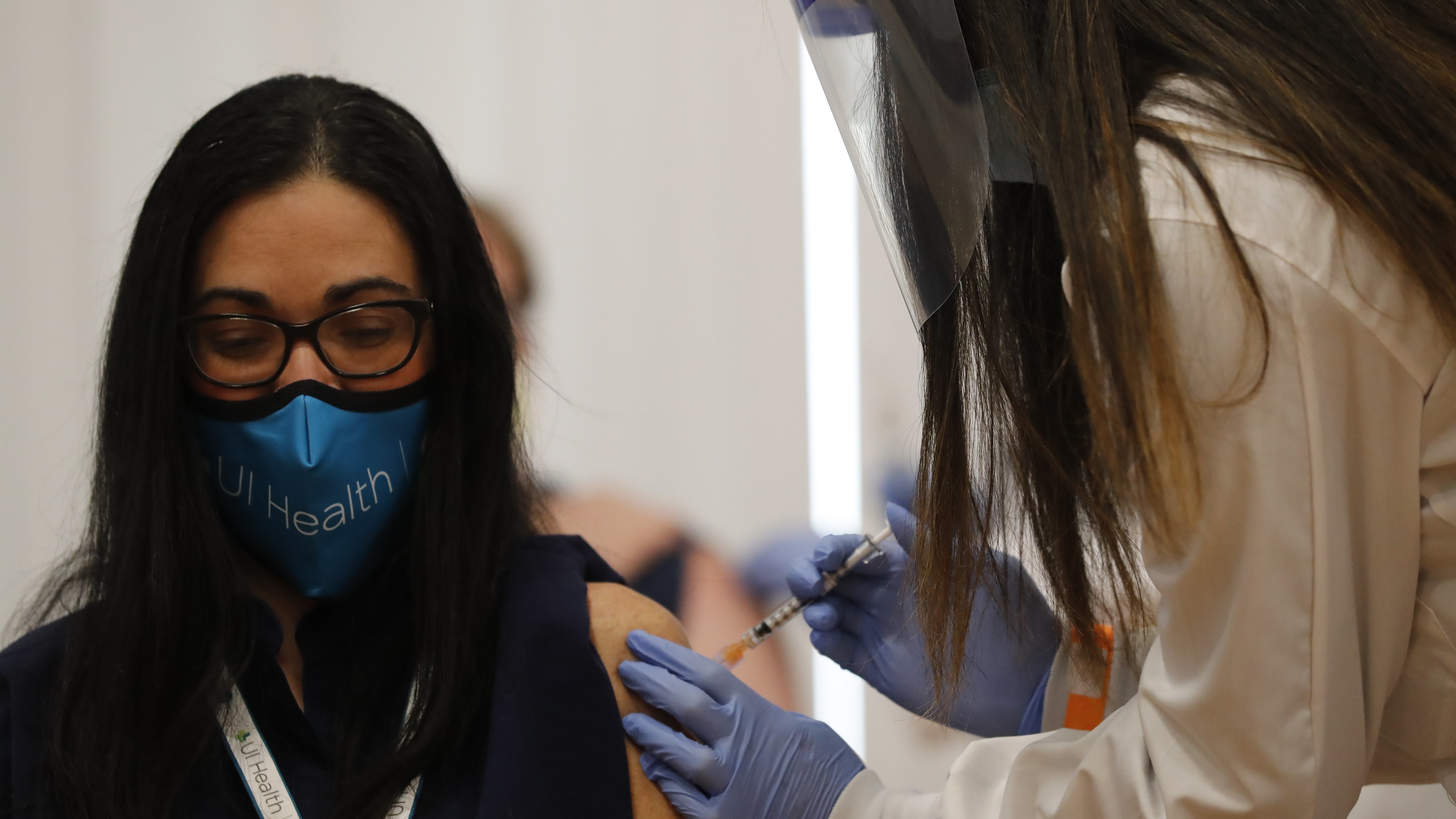 A doctor receives Chicago's first COVID-19 vaccination on Tuesday. In a new poll released the same day, respondents appeared to show less reluctance to receiving a coronavirus vaccine. (Jose M. Osorio-Pool/Getty Images)