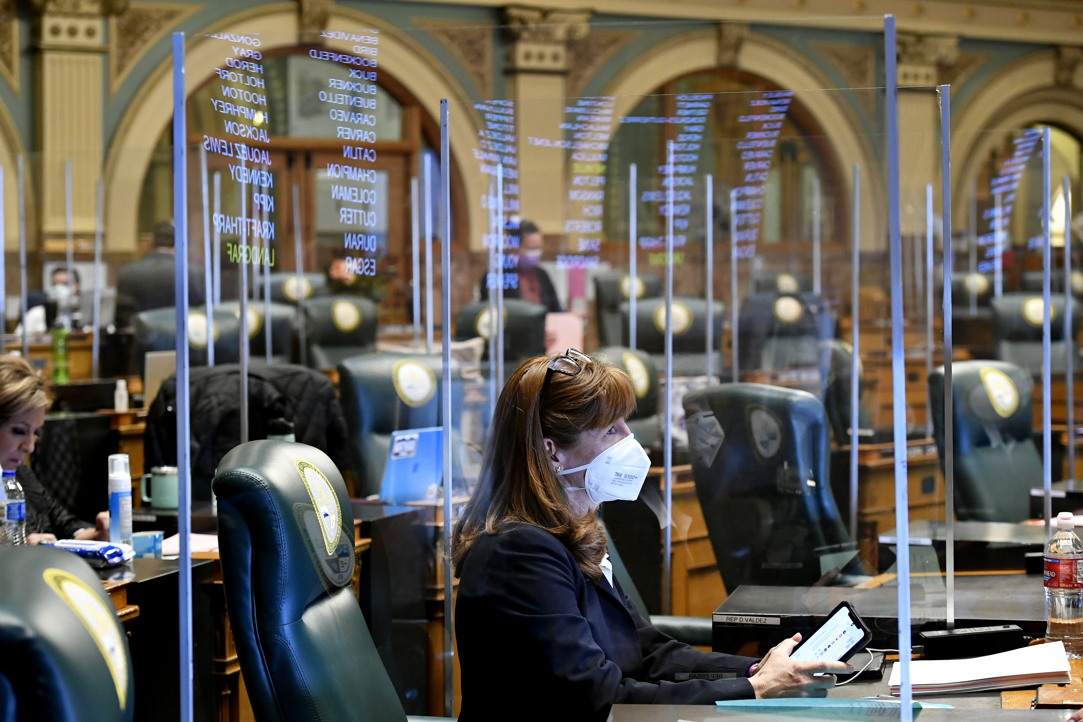 Colorado state Rep. Julie McCluskie, a Democrat, is surrounded by protective plastic barriers in the House chambers at the Colorado State Capitol during an emergency legislative session on November 30. Lawmakers there are planning to move their 2021 session back by at least a month. (Denver Post via Getty Images)
