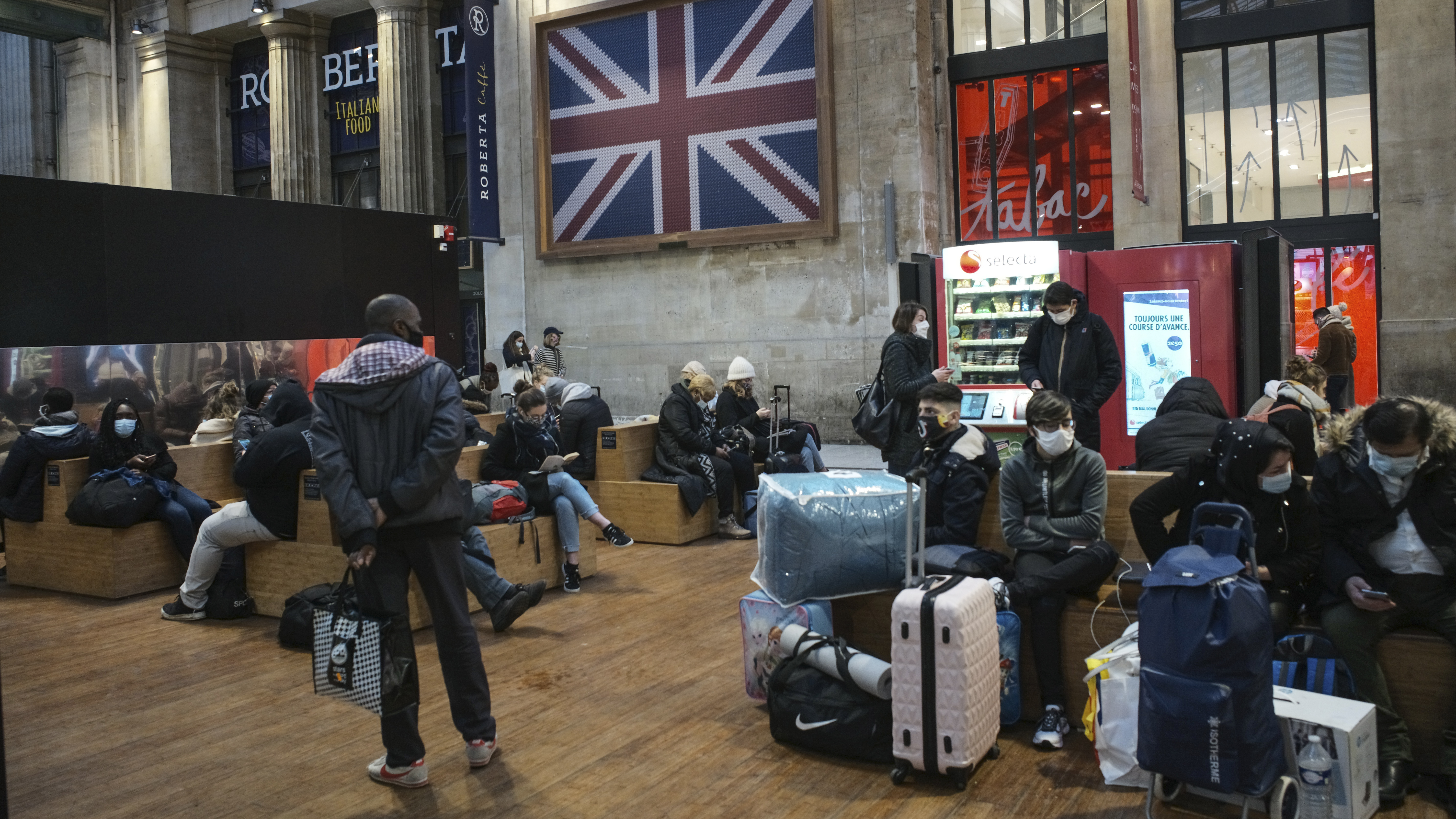 Passengers wearing face masks wait next to the Eurostar Terminal at Gare du Nord train station in Paris on Monday. France is banning all travel from the U.K. for 48 hours in an attempt to make sure that a new strain of the coronavirus in Britain doesn