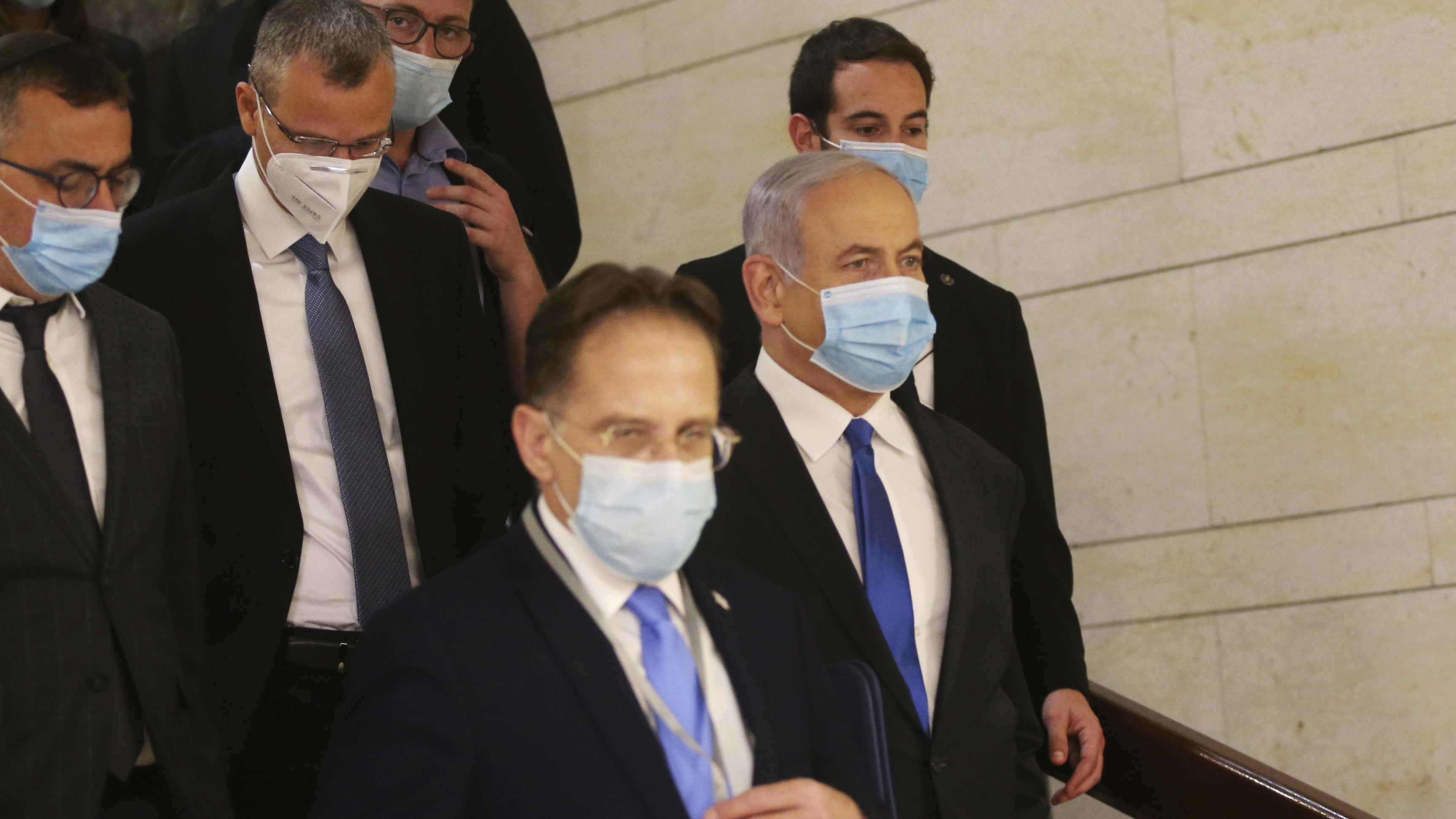 Israeli Prime Minister Benjamin Netanyahu (center) wears a protective face mask as he makes his way to attend the swearing-in ceremony of his new government, at the Knesset, Israel