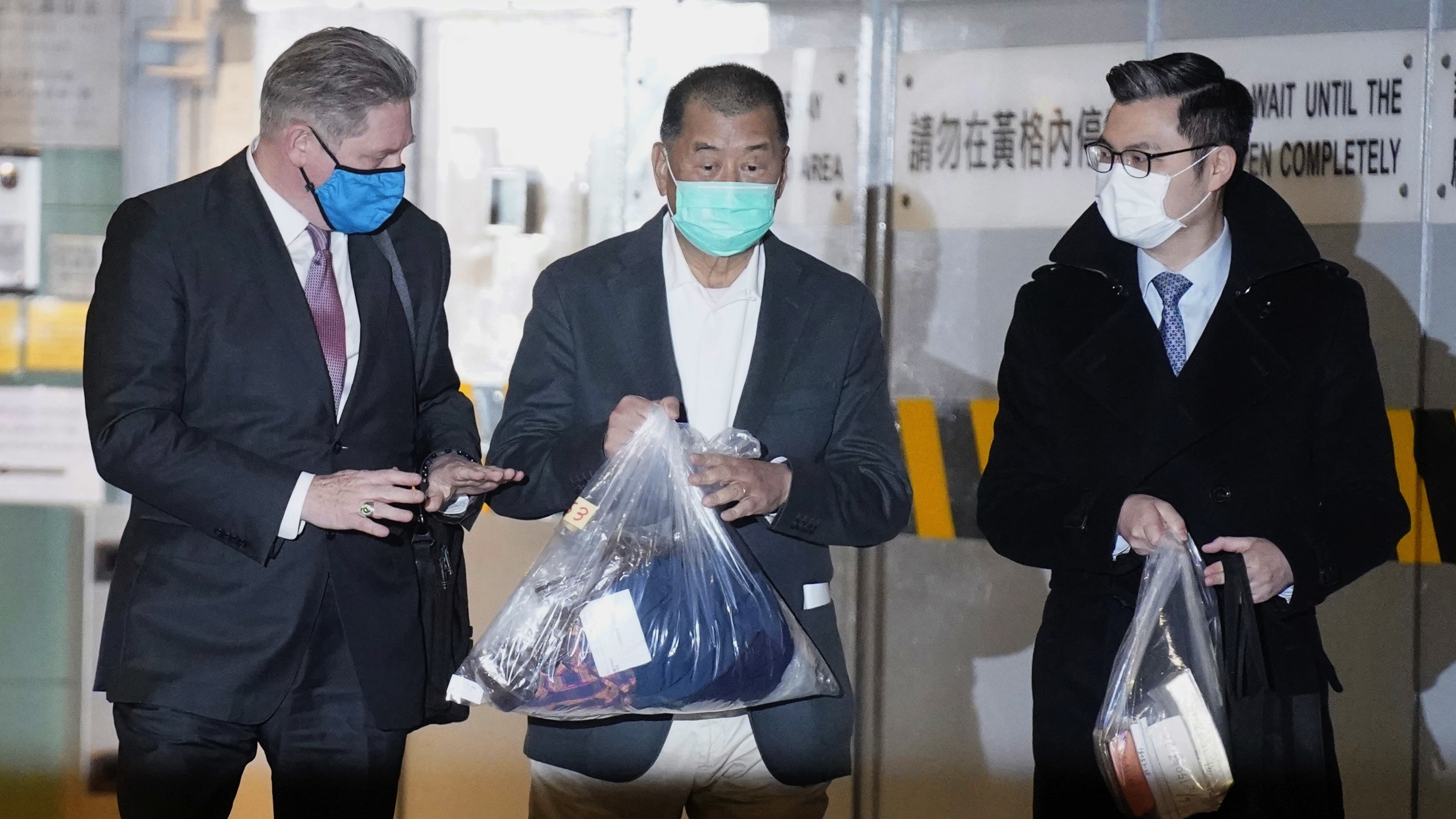 Hong Kong pro-democracy activist and media tycoon Jimmy Lai, center, walks out of court with his lawyers after being granted bail Wednesday, nearly three weeks after he was arrested over fraud and national security-related charges.