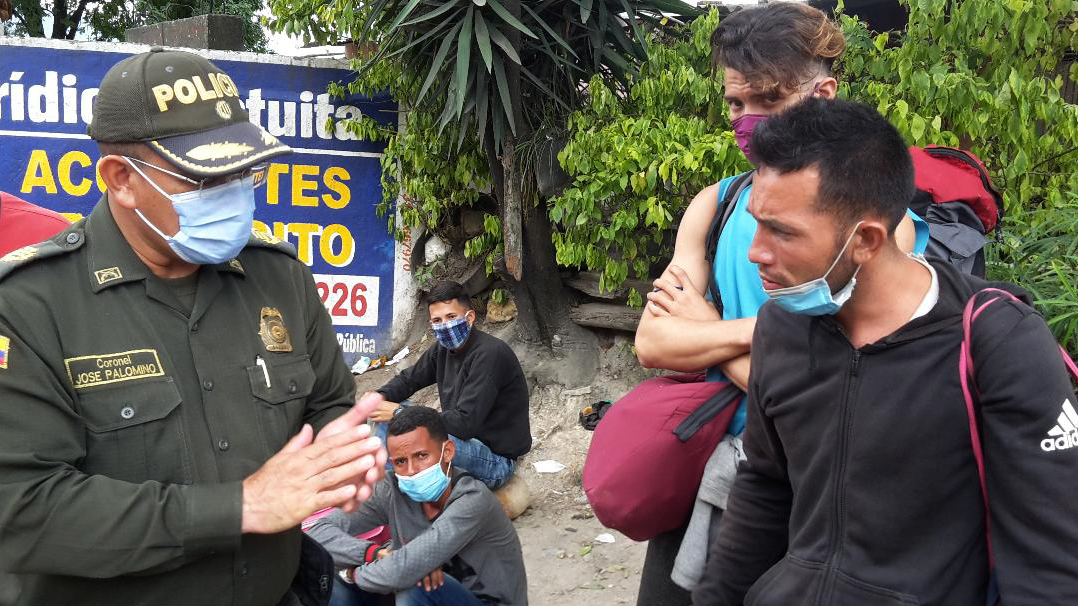 Jose Paéz (right), who migrated from Venezuela, pleads with a Colombian police officer. He was detained with about 50 other people at a roadblock in Pamplona. (John Otis for NPR)