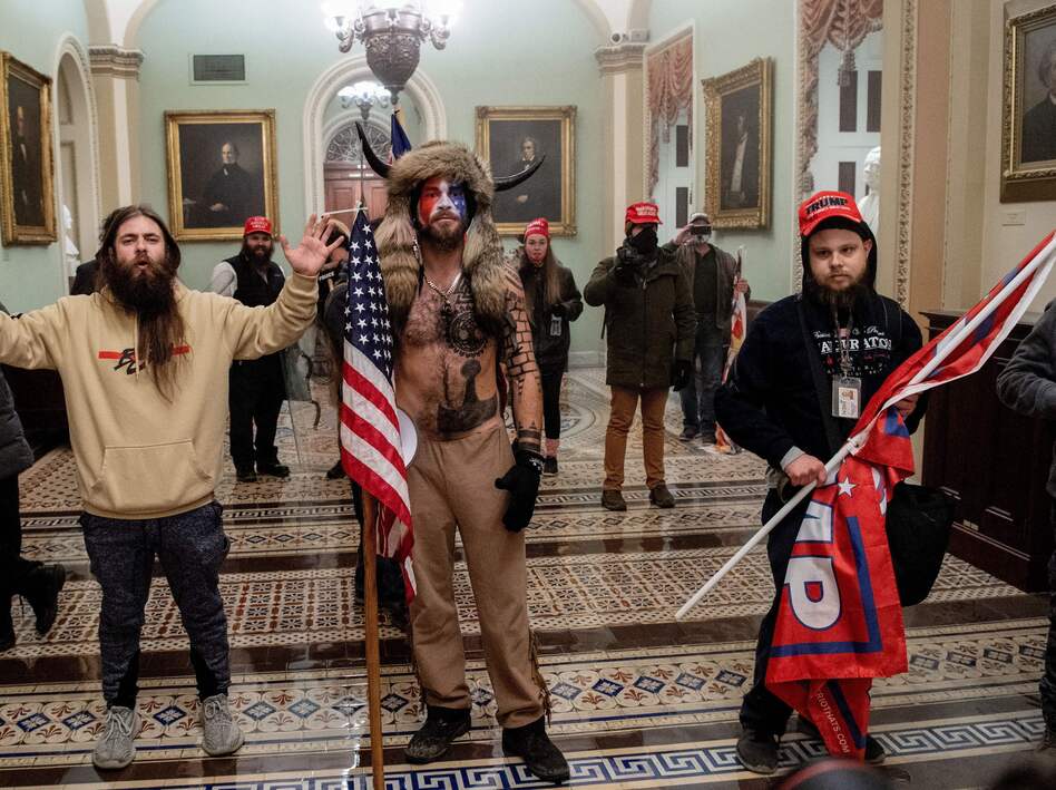 Supporters of President Trump, including Jake Angeli (center), a QAnon supporter known for his painted face and horned hat, stand inside the U.S. Capitol on Jan. 6. Demonstrators breached security and entered the Capitol as Congress was in the process of tallying the 2020 electoral vote count. (Saul Loeb/AFP via Getty Images)