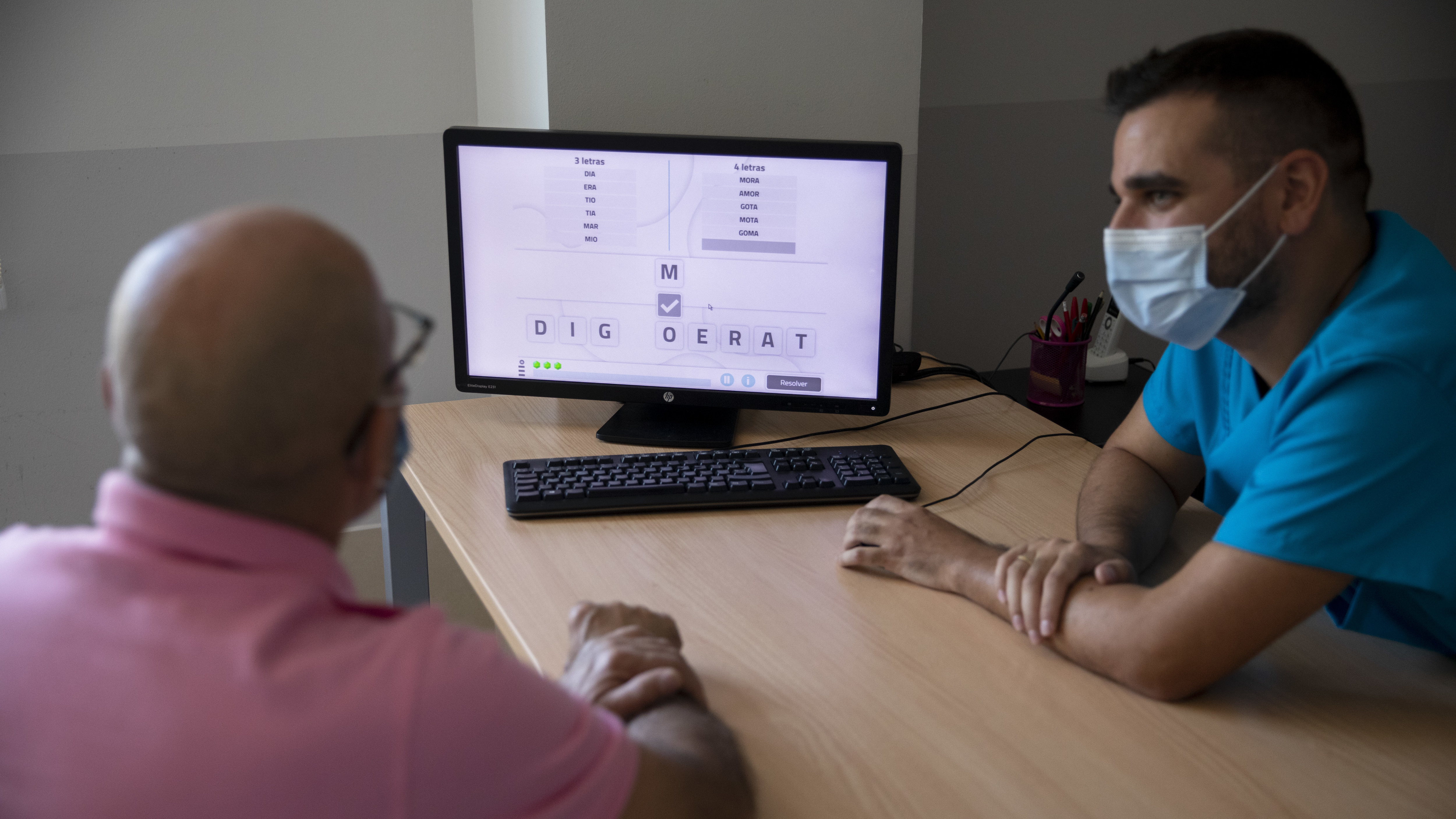Speech therapist David Romero uses software to compose words with Teodoro Leazma, who suffered COVID-19. Leazma recovered his mobility, but then realized the illness caused him to have dyslexia and other cognitive disorders. (Getty Images)