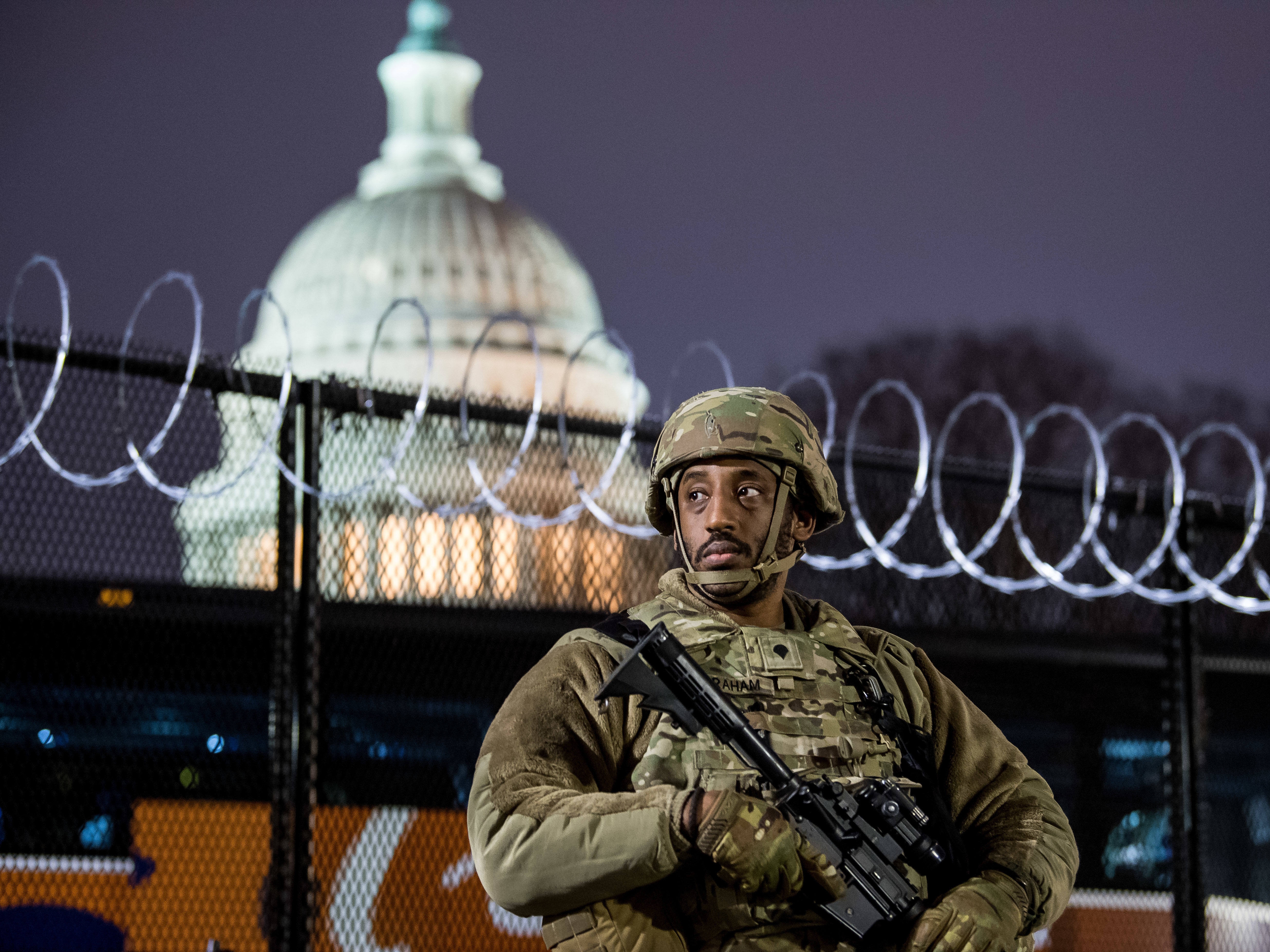 A member of the Virginia National Guard stands outside the razor wire fencing surrounding the U.S. Capitol on Friday. Up to 25,000 troops are expected by Inauguration Day. (Getty Images)