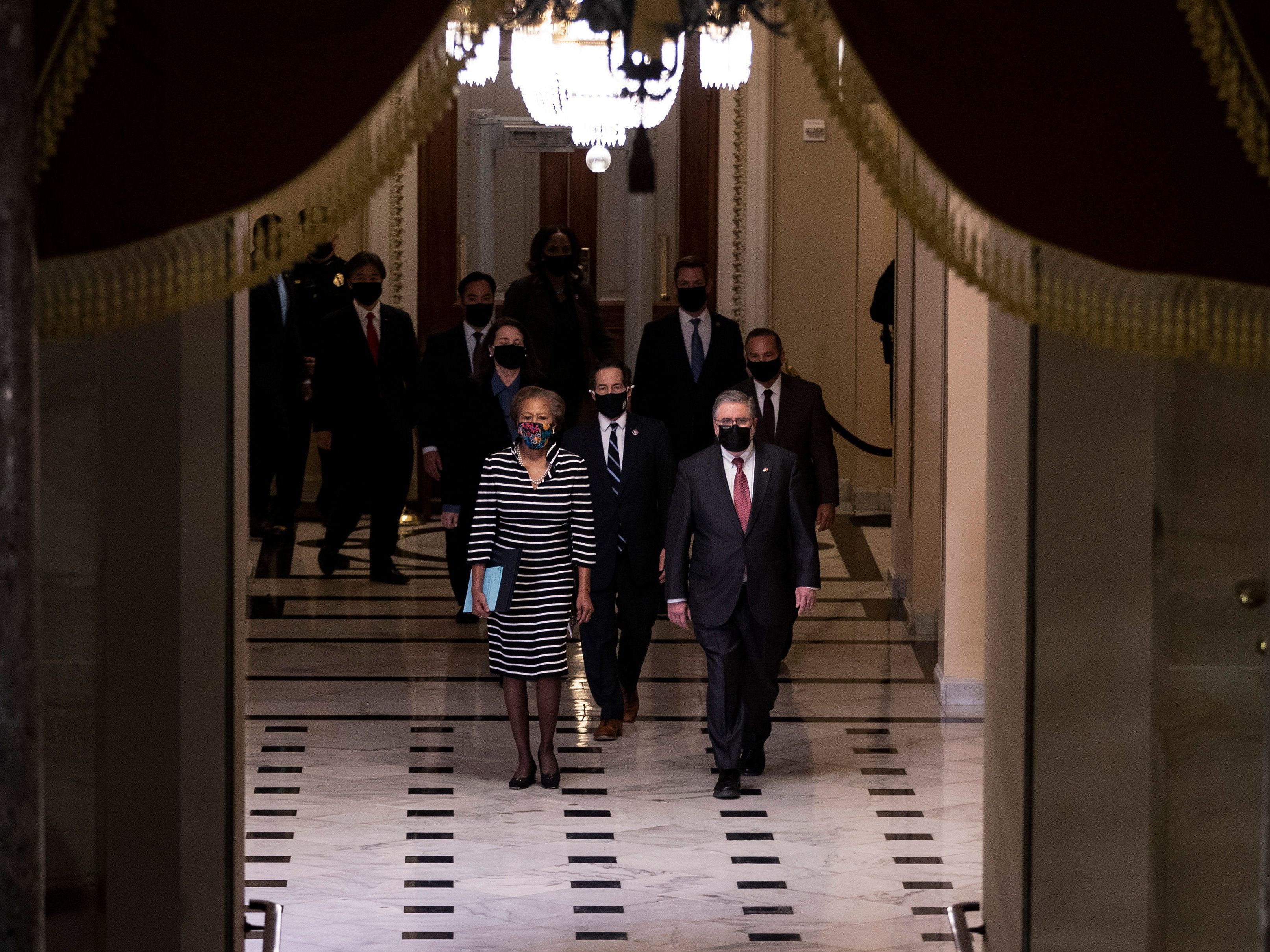 L-R: U.S. House Clerk Cheryl Johnson, Rep. Jamie Raskin and Rep. David Cicilline walk walk through the Capitol's Statuary Hall to deliver the article of impeachment for incitement of insurrection against former President Trump to the Senate floor on Monday evening. (Pool/AFP via Getty Images)