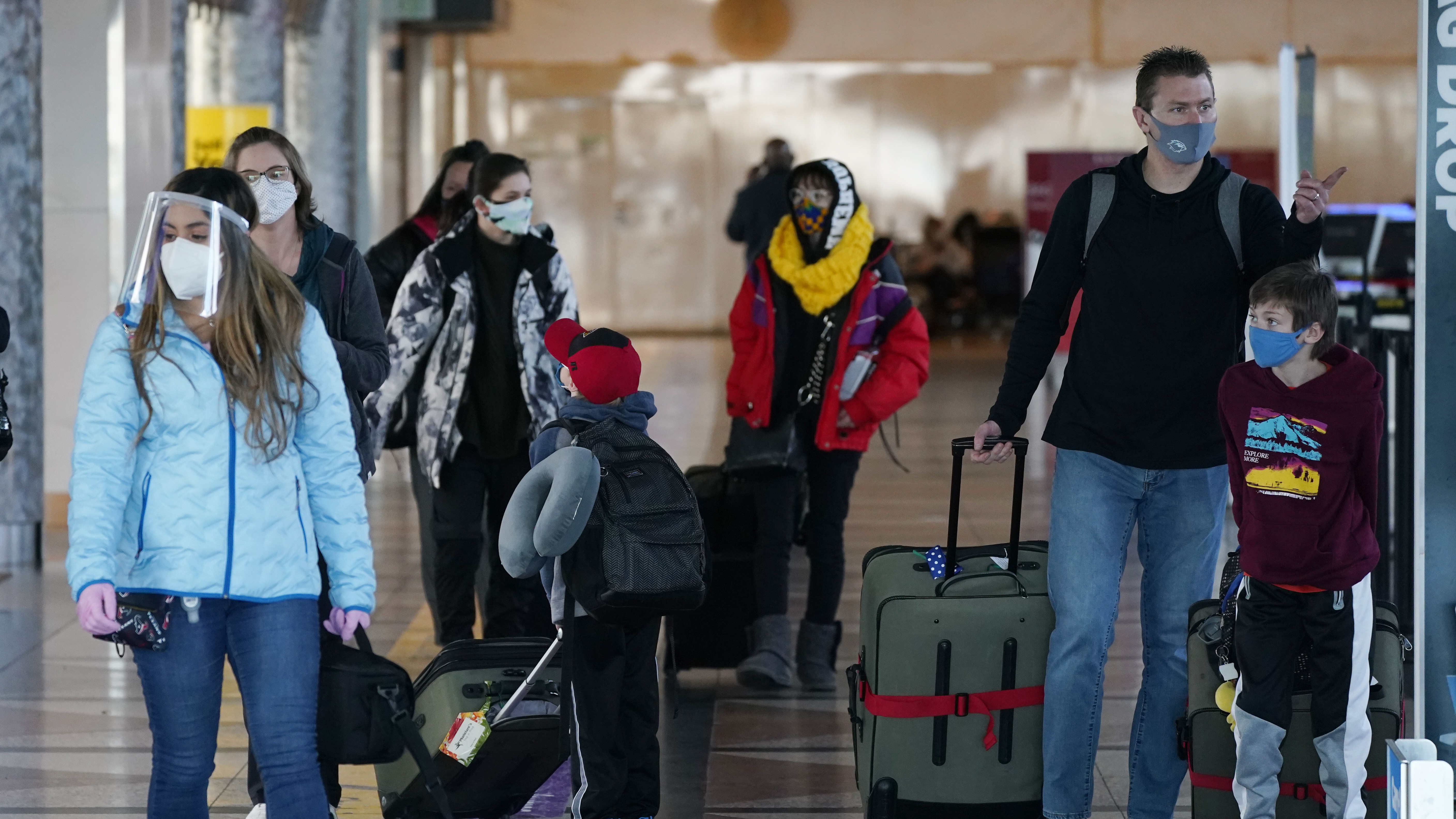 Travelers wear face masks in the main terminal of Denver International Airport on Dec. 31, 2020. Starting Feb. 1, travelers will be required to wear face masks on nearly all forms of public transportation.