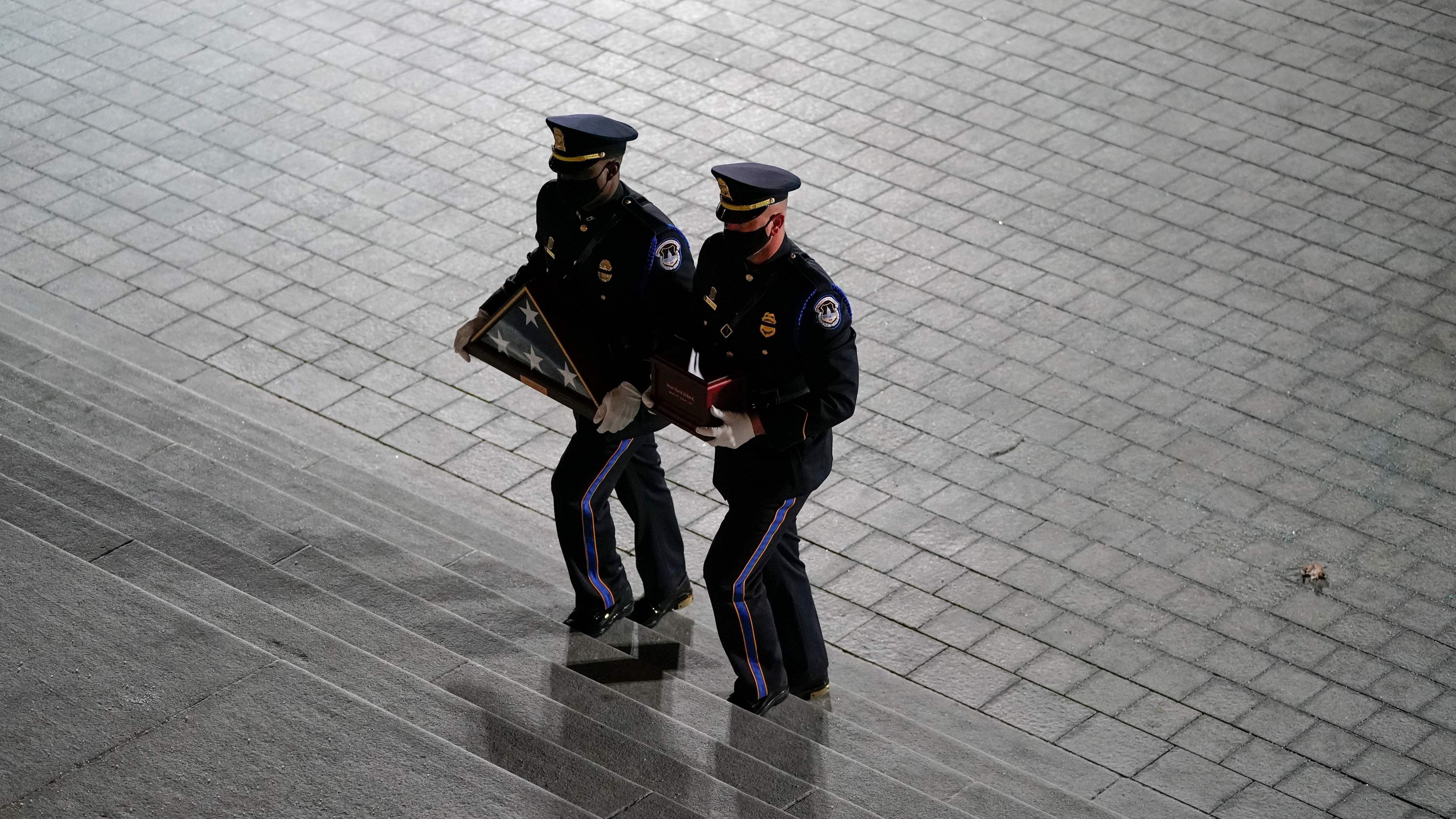 An honor guard carries an urn with the cremated remains of  Capitol Police officer Brian Sicknick and a folded American flag up the steps of the U.S. Capitol on Tuesday. (POOL/AFP via Getty Images)