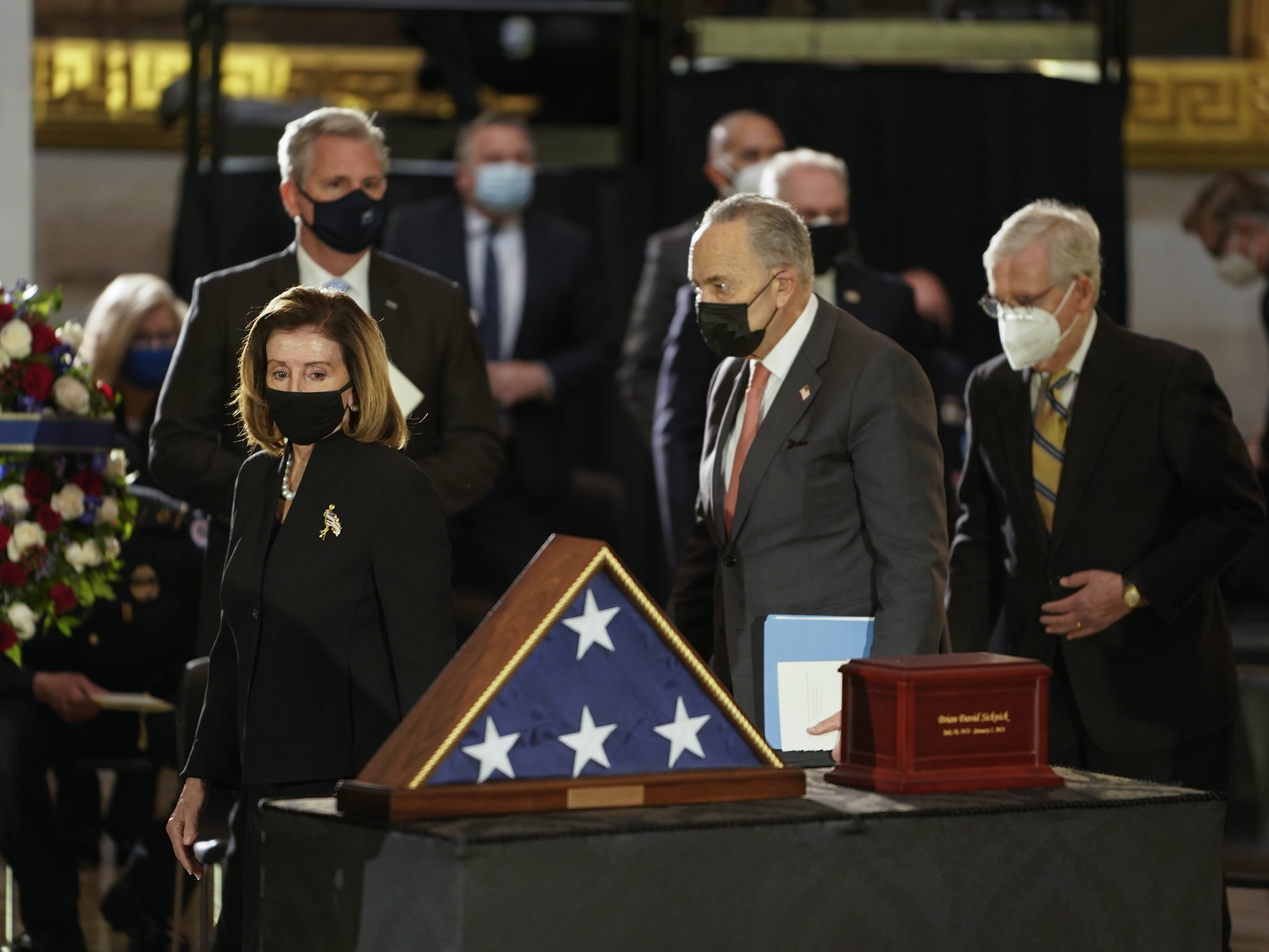 Speaker of the House Nancy Pelosi, left, and Senate Majority Leader Chuck Schumer, center, walk past the remains of U.S. Capitol Police Officer Brian Sicknick as he lies in honor in the Rotunda of the Capitol on Wednesday. (Getty Images)
