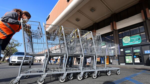 An employee pushes carts in Long Beach, Calif., at a Kroger store. The supermarket chain announced a $100 incentive bonus Friday for employees who receive a COVID-19 vaccine.