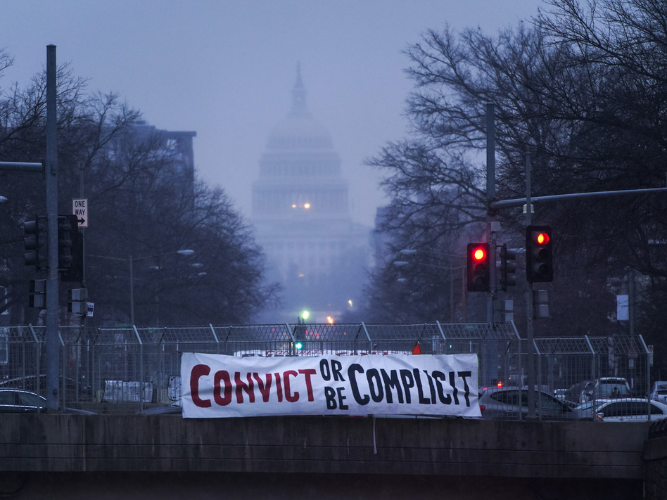 A sign reading "Convict or Be Complicit" hangs from a bridge on North Capitol Street in Washington, D.C., on the second day of former President Donald Trump's second impeachment trial. (Drew Angerer/Getty Images)