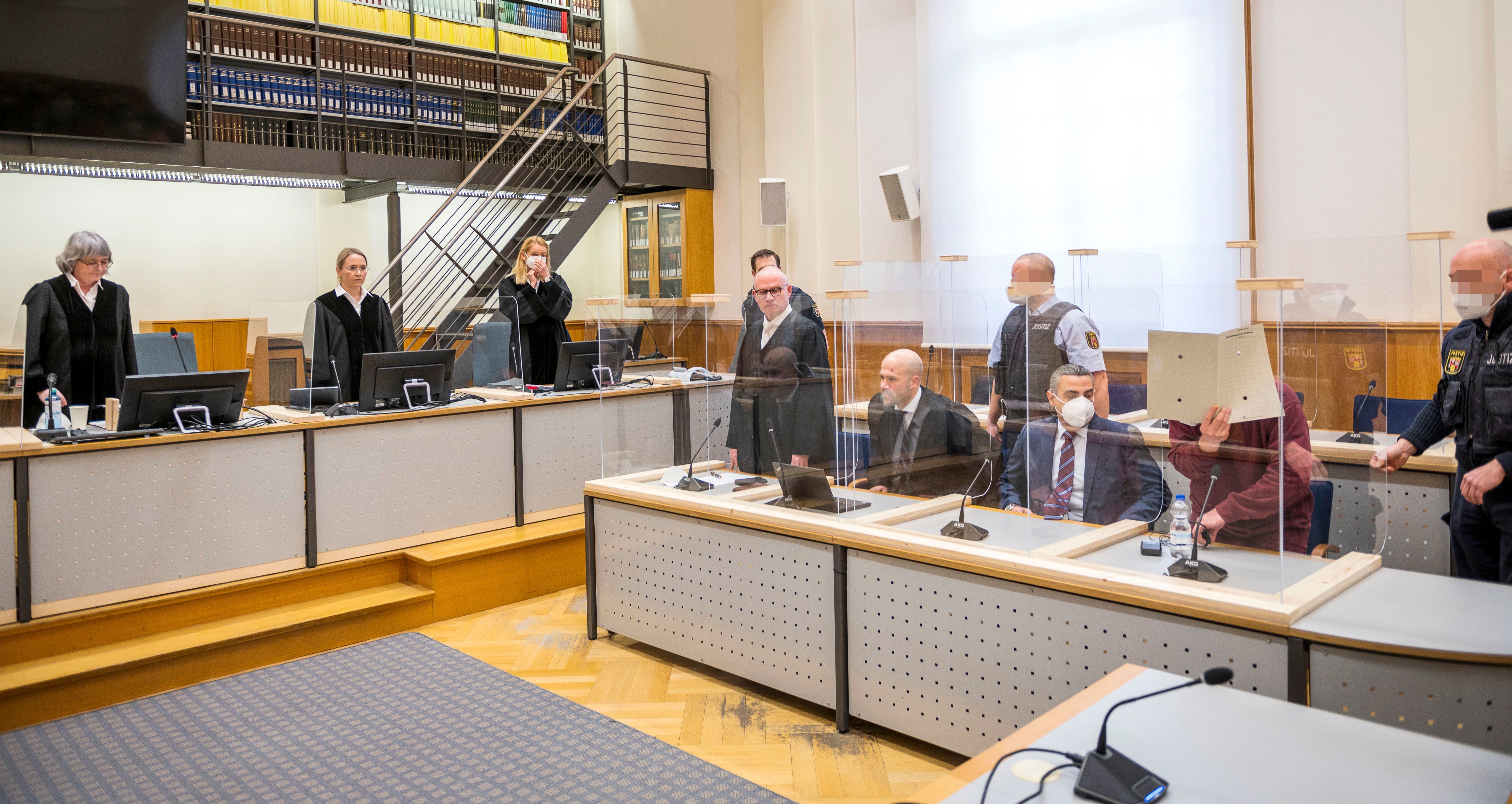 Presiding judge Anne Kerber (left) stands before handing the verdict to Syrian defendant Eyad al-Gharib (right, face hidden under a folder) Wednesday in Koblenz. Gharib, 44, a former Syrian intelligence service agent, was sentenced to 4 1/2 years in jail for complicity in crimes against humanity in the first court case over state-sponsored torture by the Syrian government. (AFP via Getty Images)