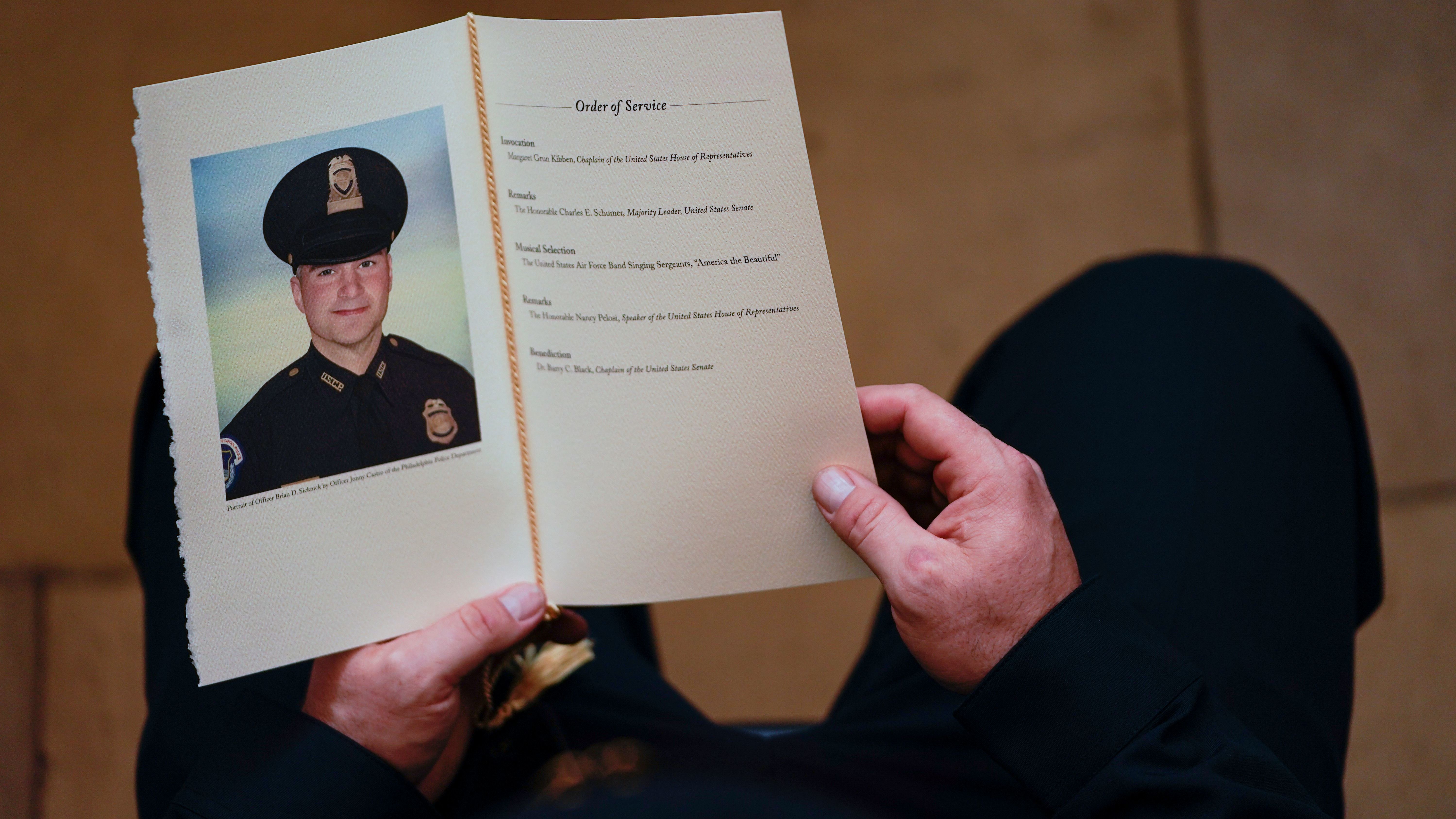 A Capitol Police officer holds a program as people pay their respects at the remains officer Brian Sicknick, who died after defending the Capitol against the Jan. 6 insurrection. (Pool/AFP via Getty Images)