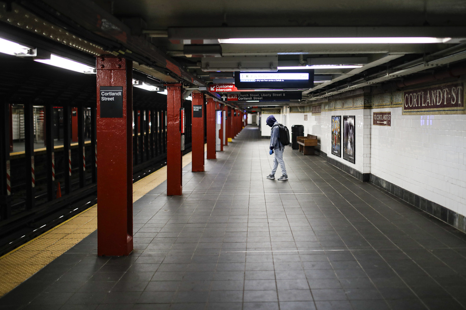 A person wears protective gloves and a face mask due to COVID-19 concerns while walking along an empty train platform at the Cortlandt Street station on March 21, 2020, in the Brooklyn borough of New York City.