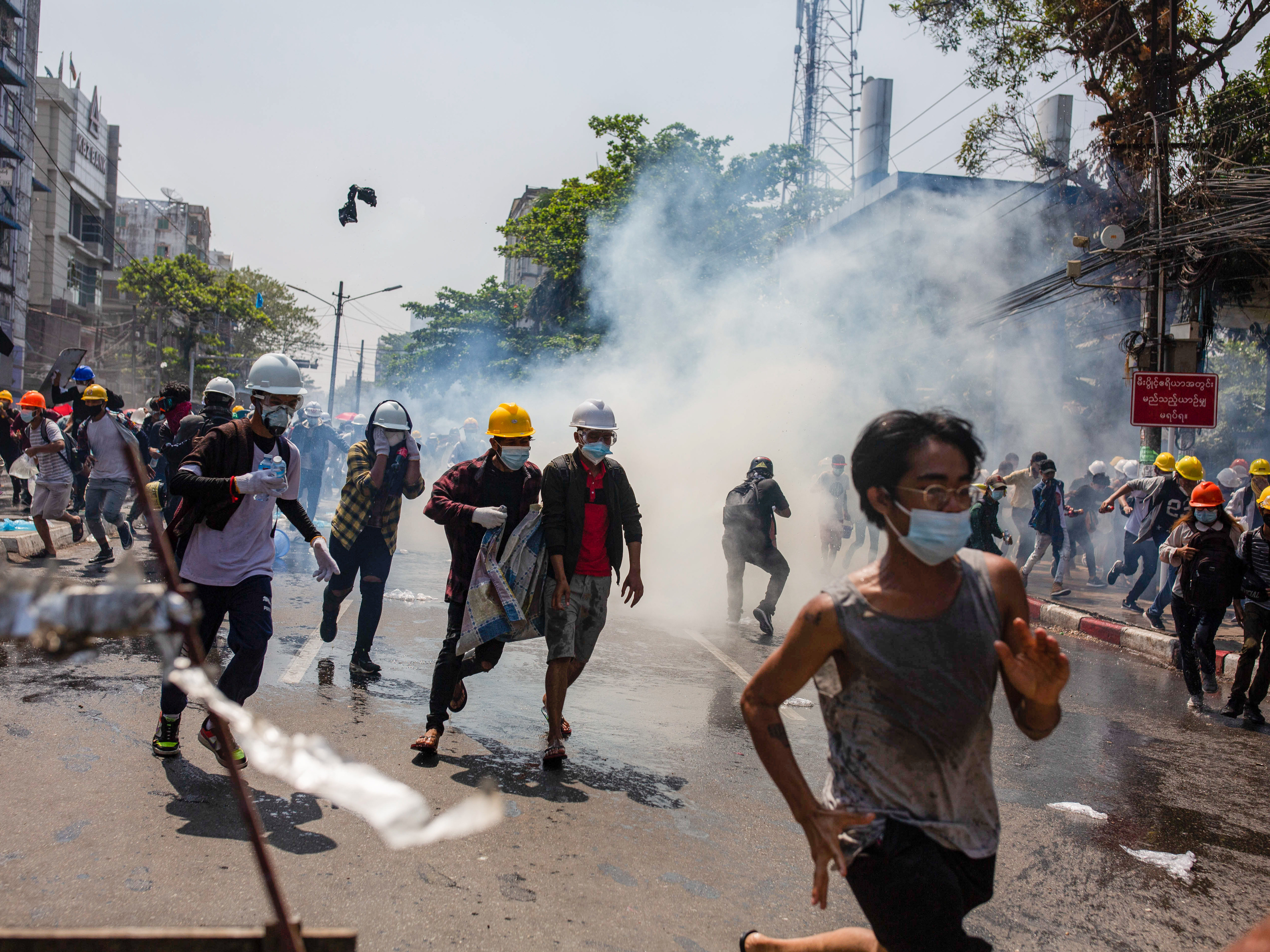 Anti-junta protesters run from teargas fired by police during a demonstration in Yangon on Monday. At least 18 people were killed over the weekend as Myanmar police reportedly used live ammunition against protesters. (SOPA Images/LightRocket via Gett)