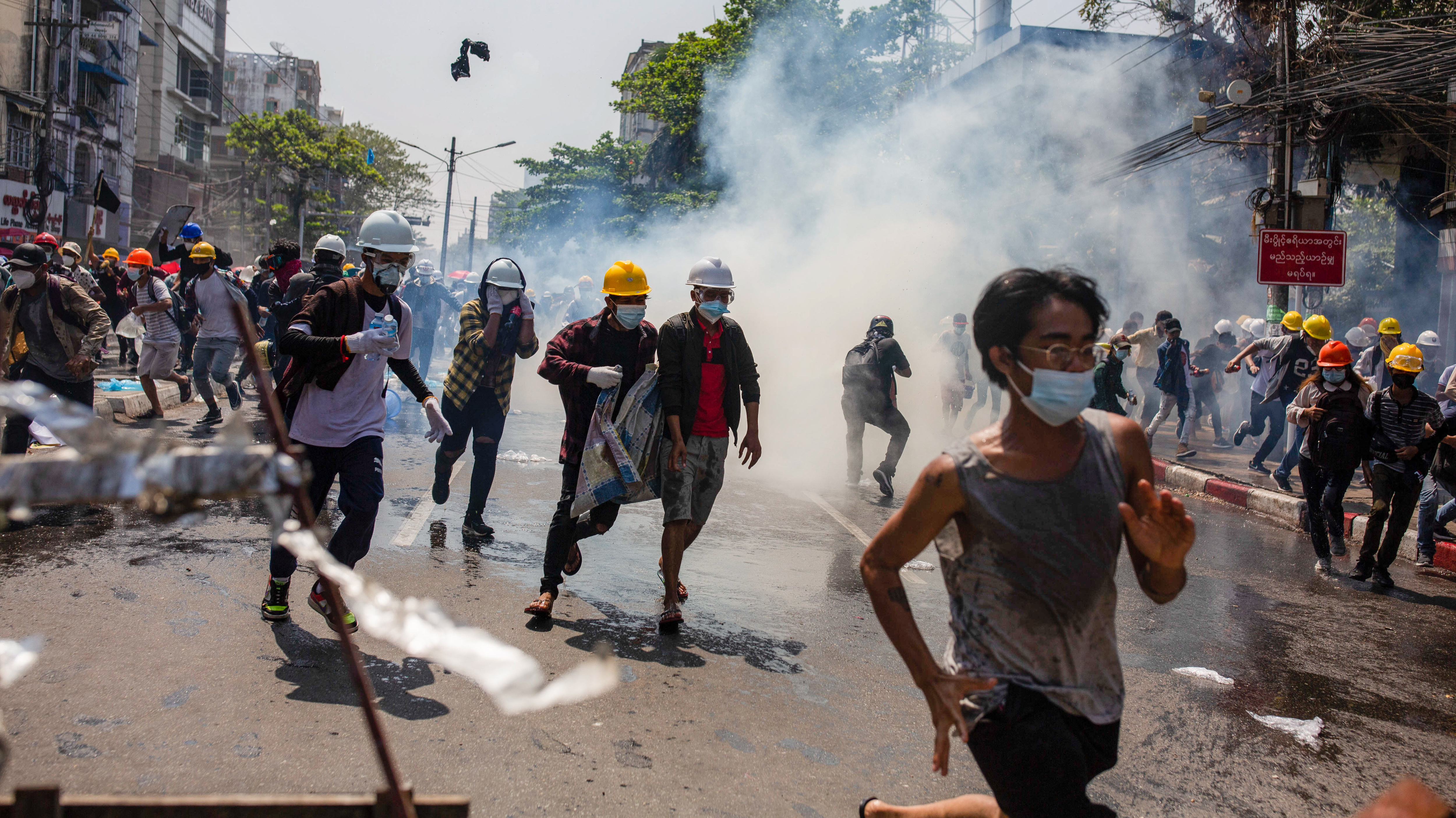 Anti-junta protesters run from teargas fired by police during a demonstration in Yangon on Monday. At least 18 people were killed over the weekend as Myanmar police reportedly used live ammunition against protesters.